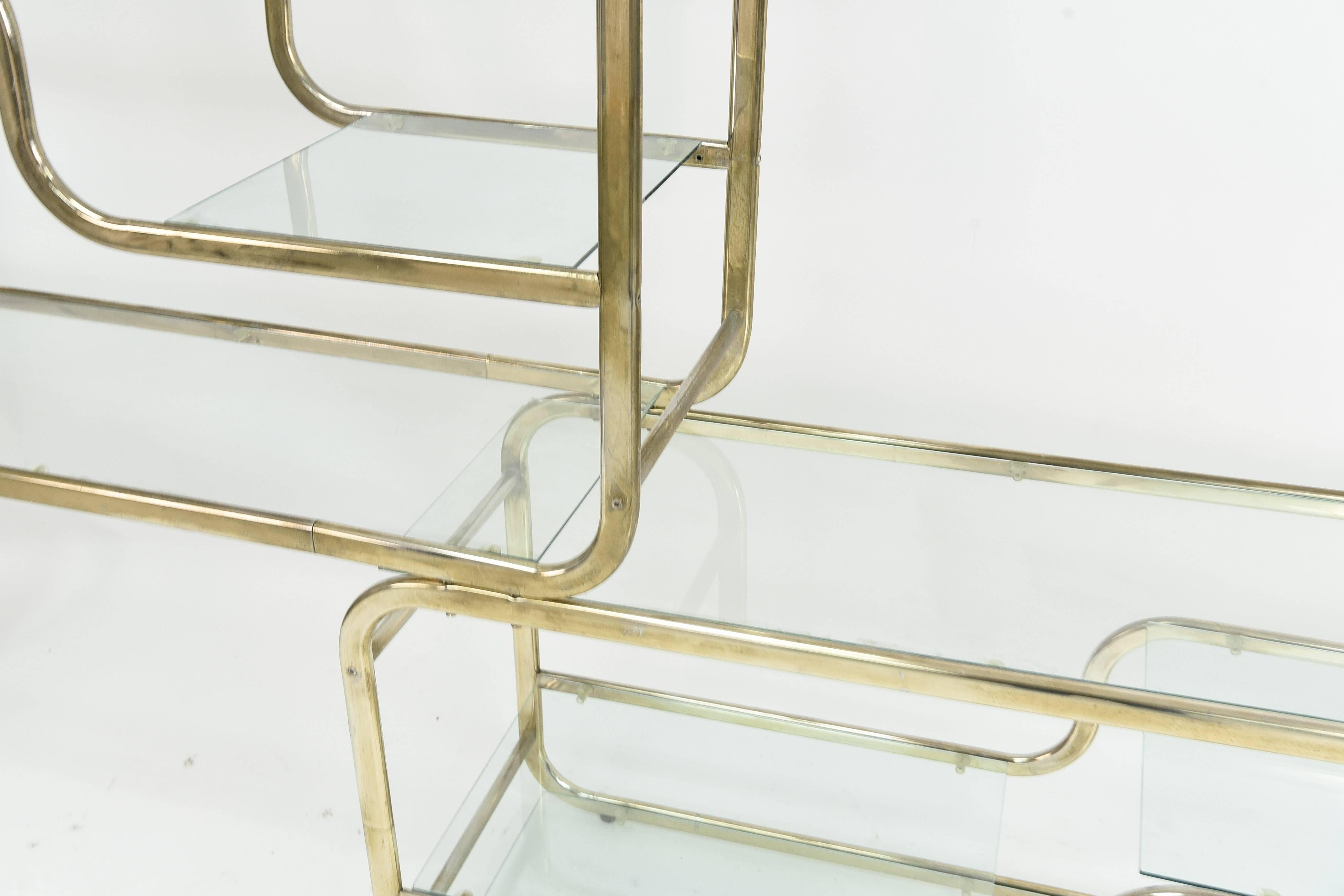 This modular, cantilever brass and glass étagère is in the manner of sought after midcentury designer Milo Baughman. This piece resembles Baughman's étagère design for D.I.A. and is of a creative, sculptural form. The underside piece can be moved to