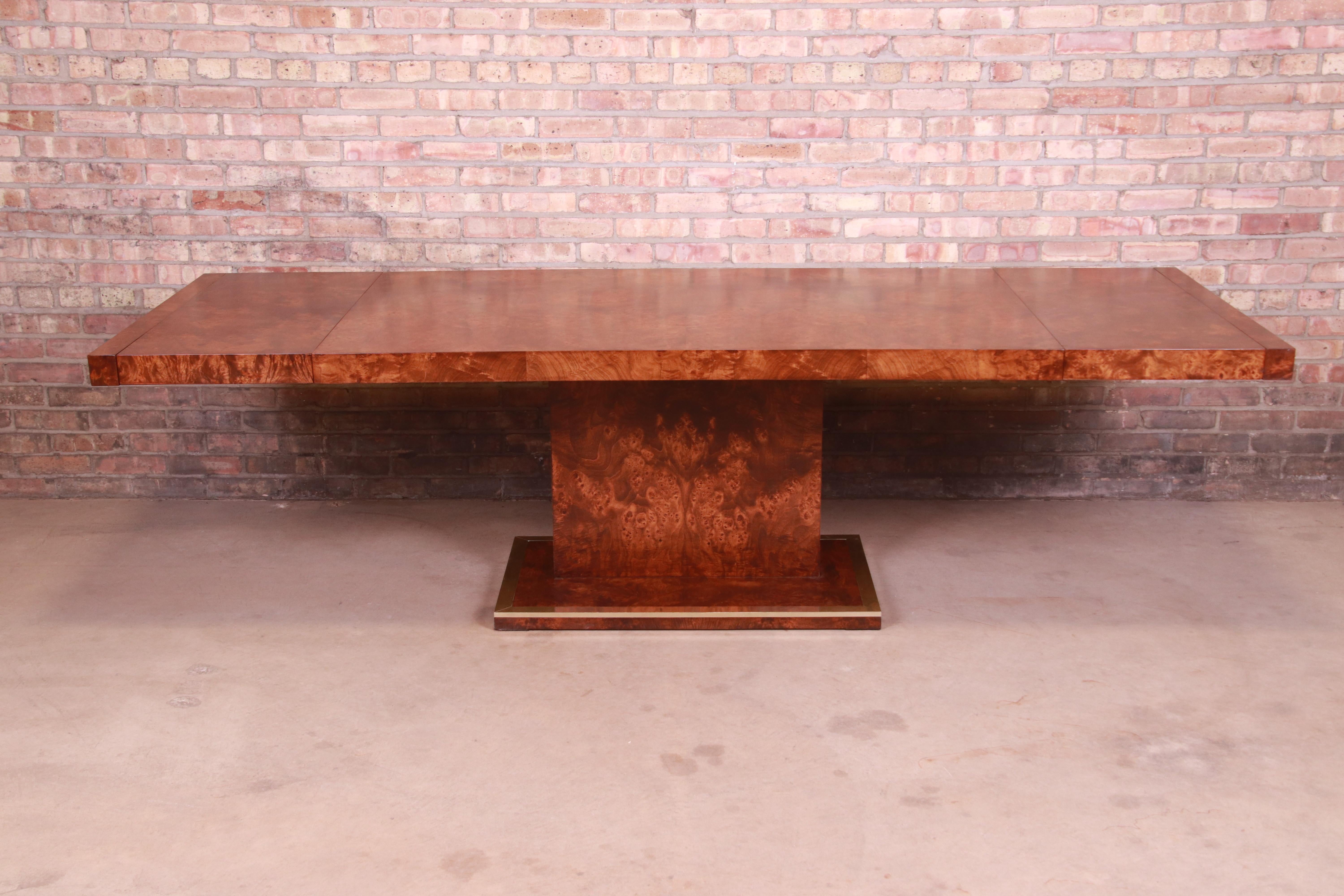 An exceptional Mid-Century Modern pedestal extension dining table

In the manner of Milo Baughman,

USA, 1970s

Burled olive wood, with brass trim on pedestal base.

Measures: 68