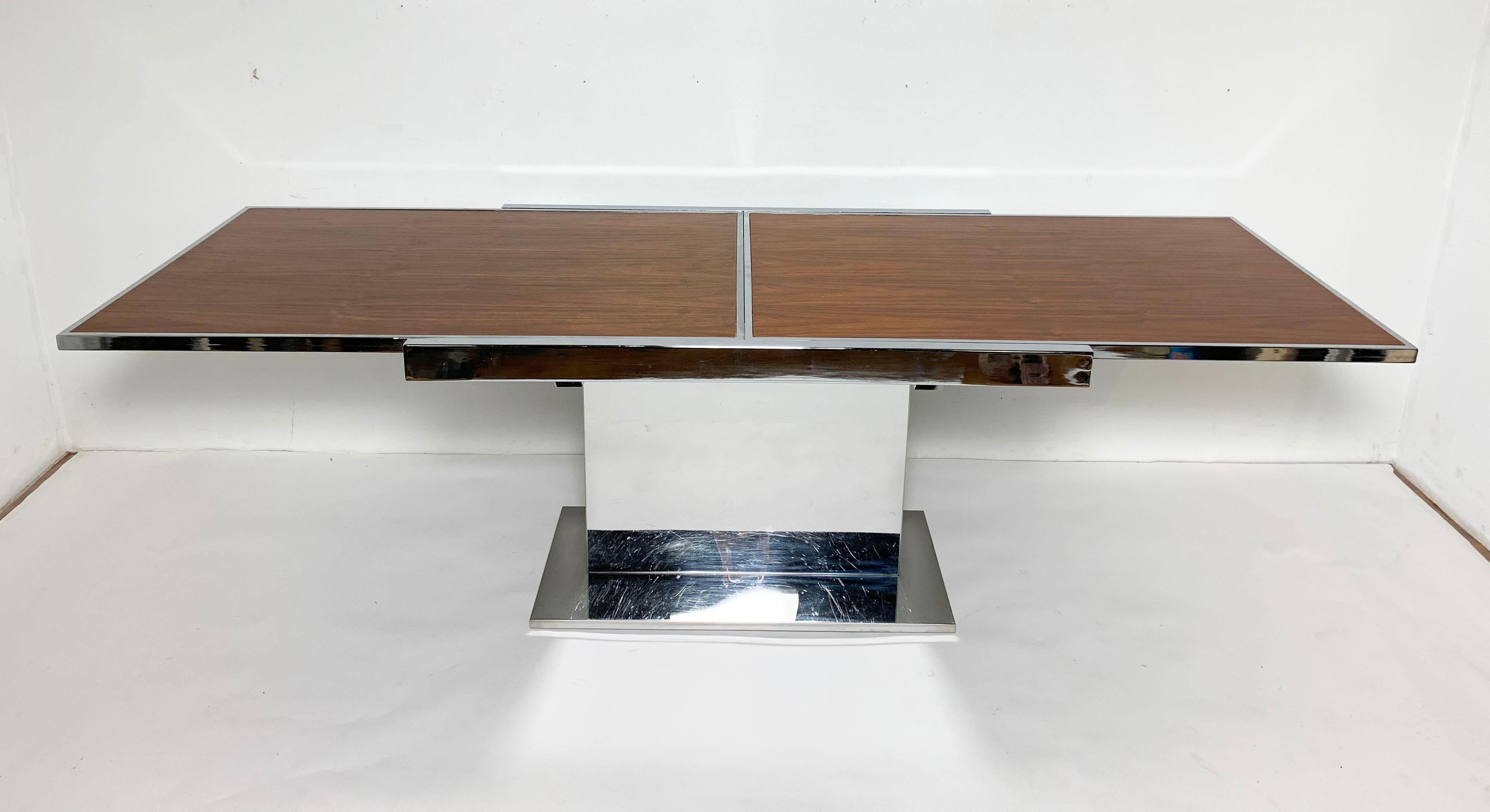 An expandable dining table by Thomasville’s Founders division, in the manner of Milo Baughman, in walnut and chromed steel, circa 1960s.

Measures 47.25