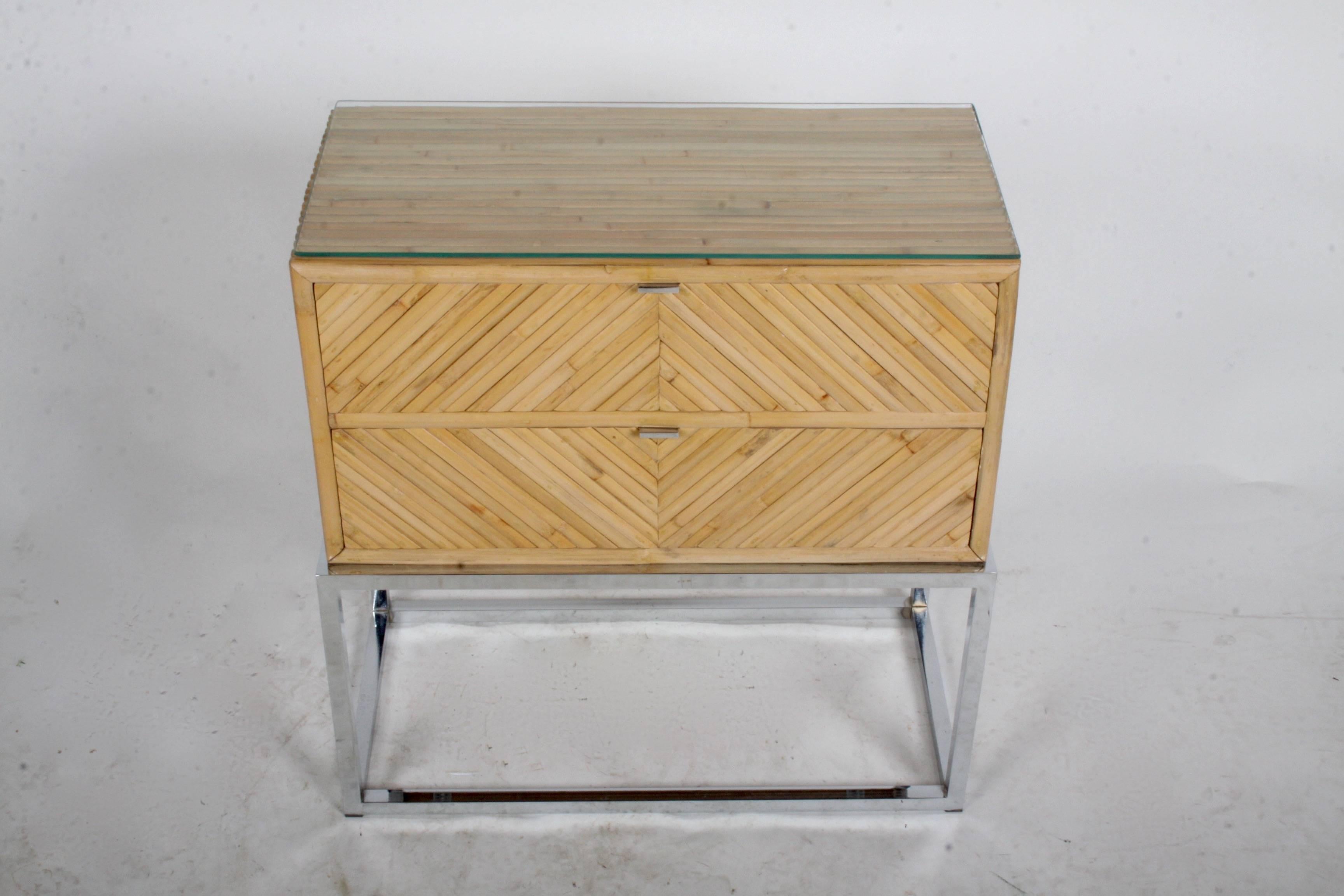 A single two-drawer chest, end table or nightstand, in the style of Milo Baughman. Having a geometric pattern in bamboo on chrome tube base, with chromed-plated flat pulls. Glass top.