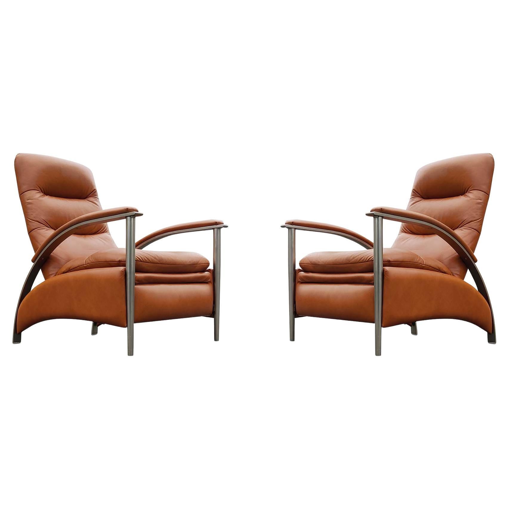 A very stylish and super comfortable pair of 'Radius' reclining lounge chairs, in the manner of Milo Bauhgman. American-made, circa 1990s or early 2000s, this substantial pair of chairs has a very attractive orange-brown leather upholstery. The