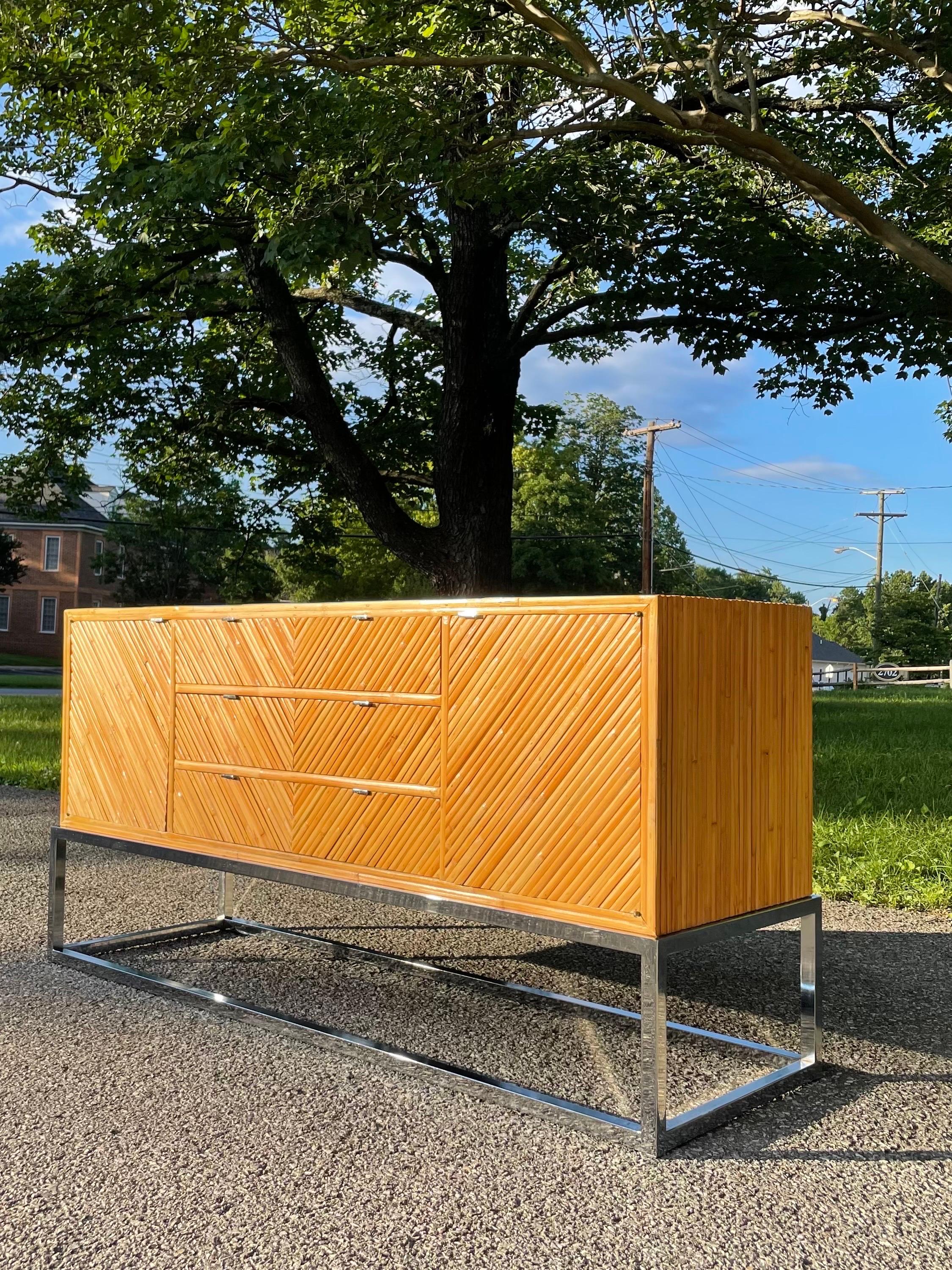 Gorgeous split reed bamboo credenza in beautiful condition with chrome base circa 1970s. Credenza is finished on all sides allowing piece to stand freely in the room. An incredible piece that would go well with almost any style. 

Other notable