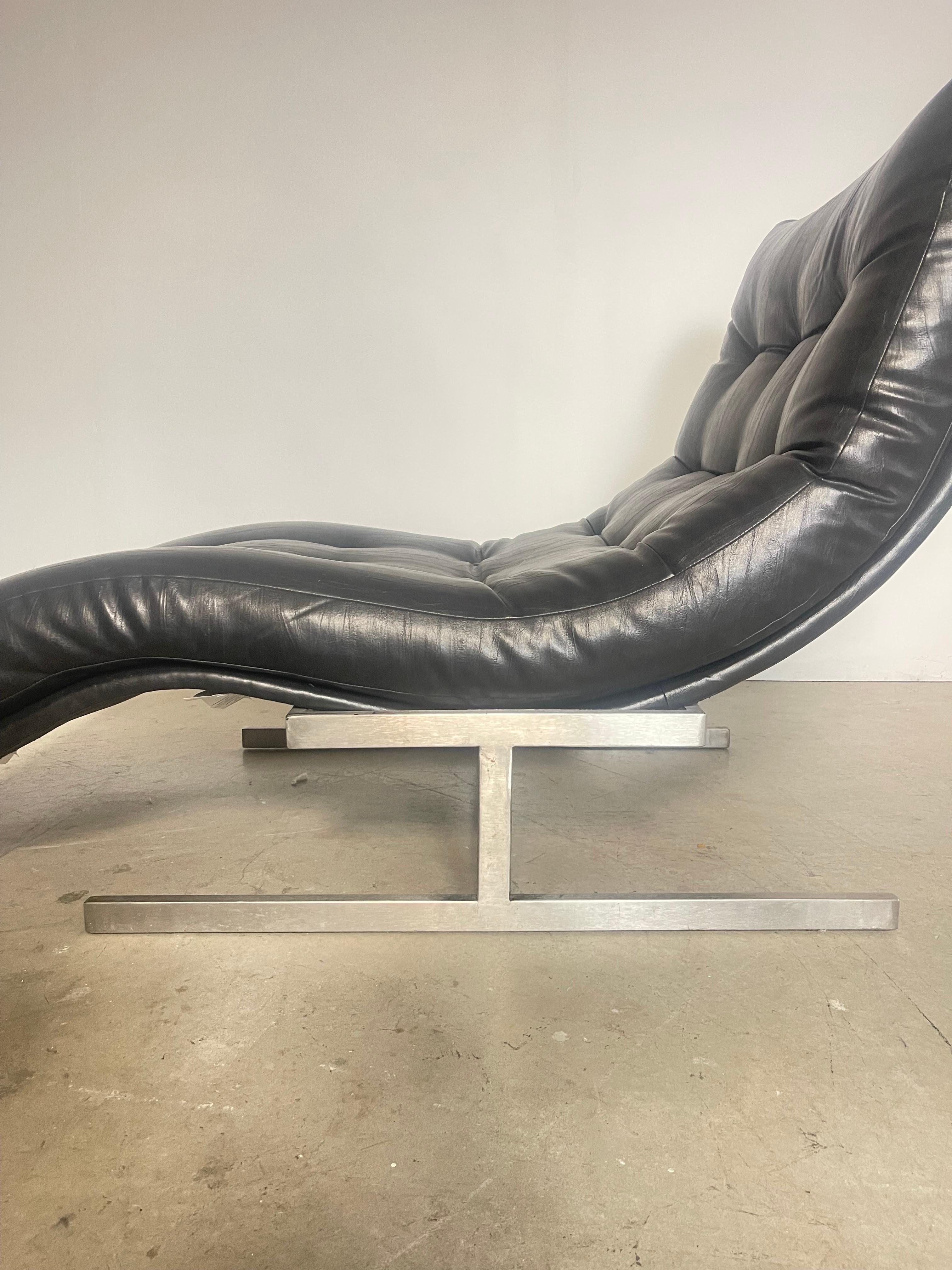 Chaise lounge in faux leather attributed to designer Milo Baughman. Faux leather shows minor wear at corners, overall good condition. Some minor wear to the frame. 