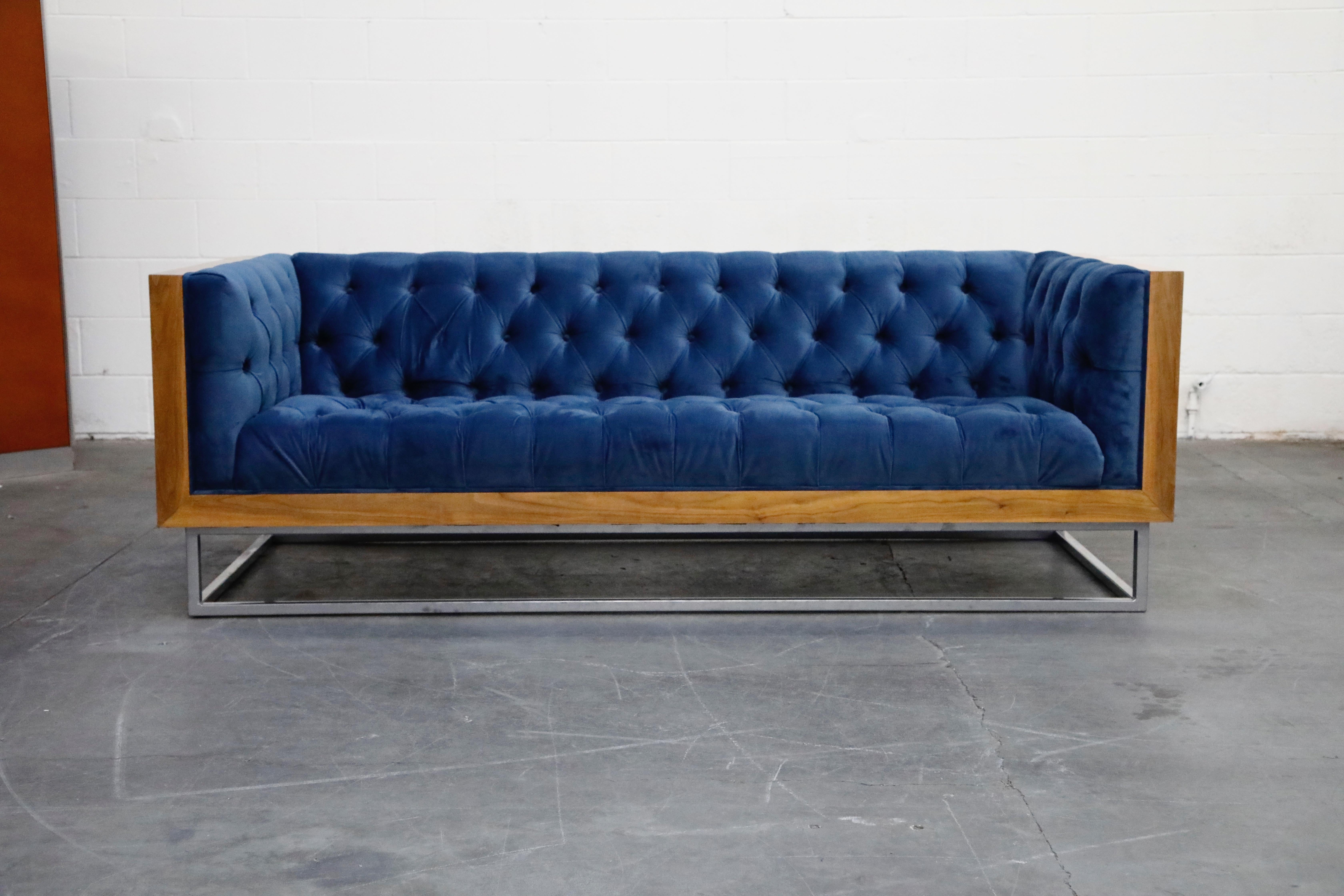 This high quality, well made custom case sofa in the style of Milo Baughman for Thayer Coggin features a hefty wood case design floating on top of a thick steel base. The vibrant blue velvet tufted upholstery features one row of buttons in
