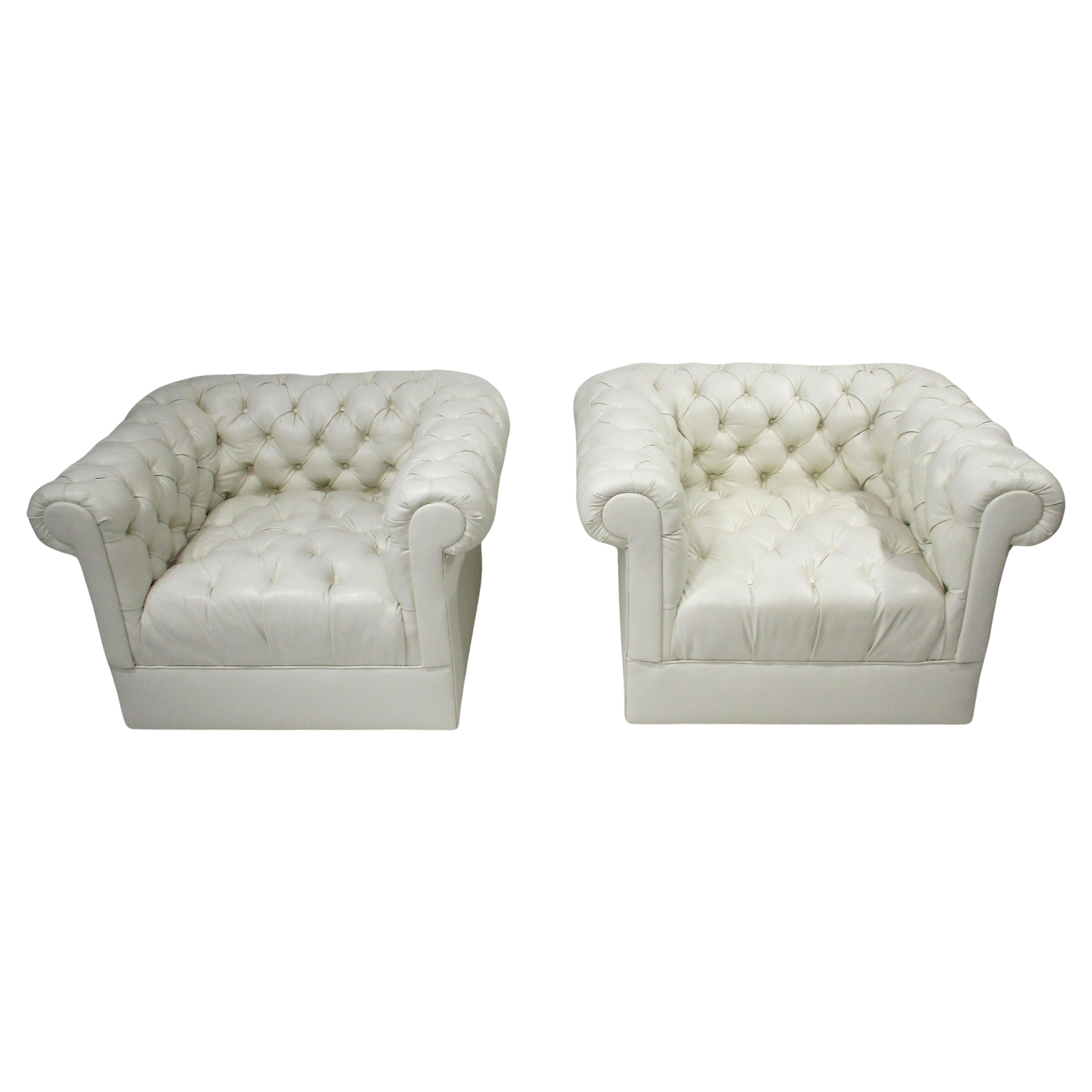 Un par de lujosas y sofisticadas tumbonas cubo empenachadas con tapicería de polipiel blanca . Estos sillones suaves y cómodos serían una declaración de intenciones en cualquier interior o espacio con un aspecto retro de chesterfield diseñado a la