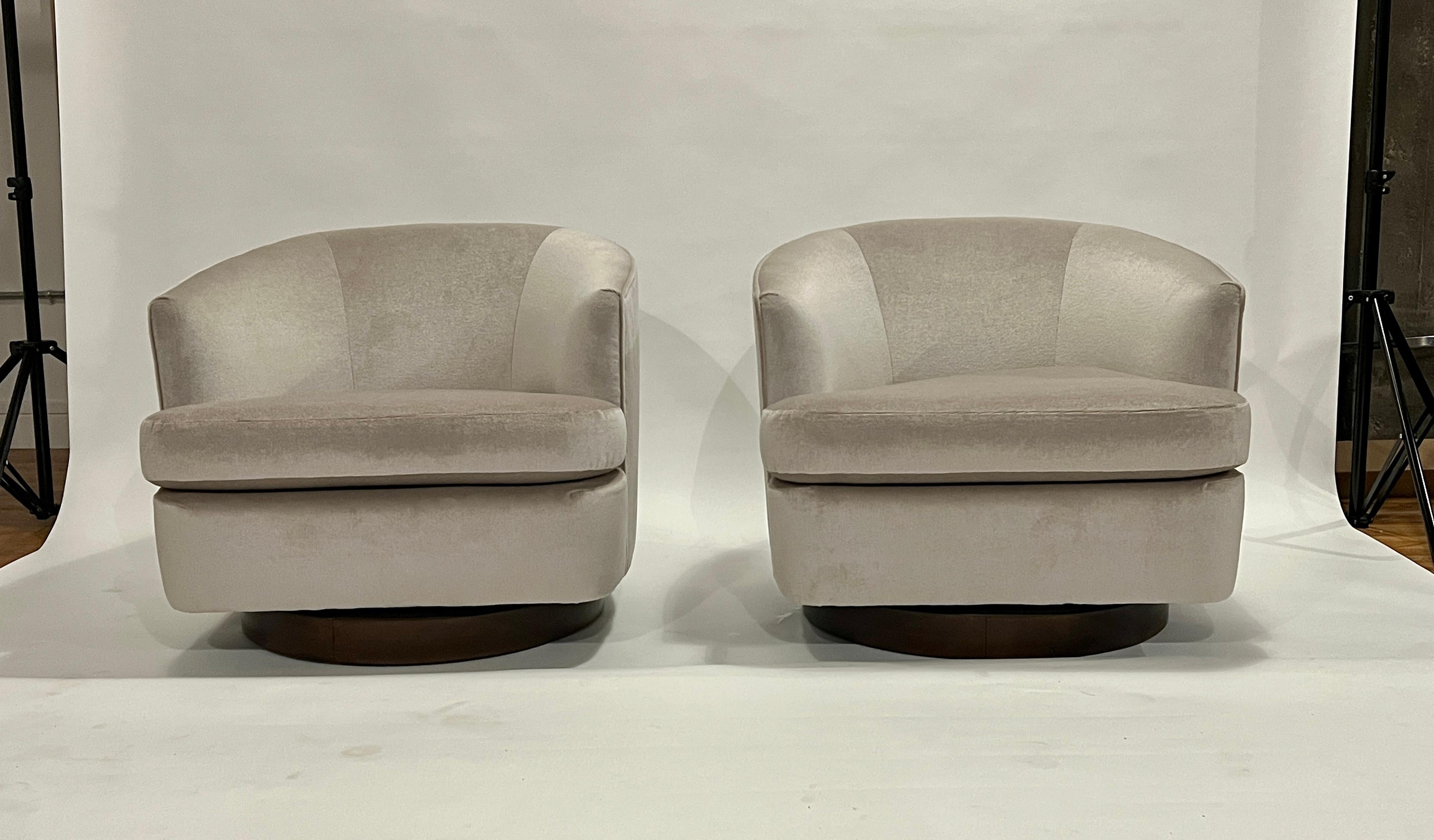 Pair of Milo Baughman style swivel armchairs newly upholstered in a platinum color mohair and restored walnut bases. These restored chairs have removable seat cushions upholstered on each side.