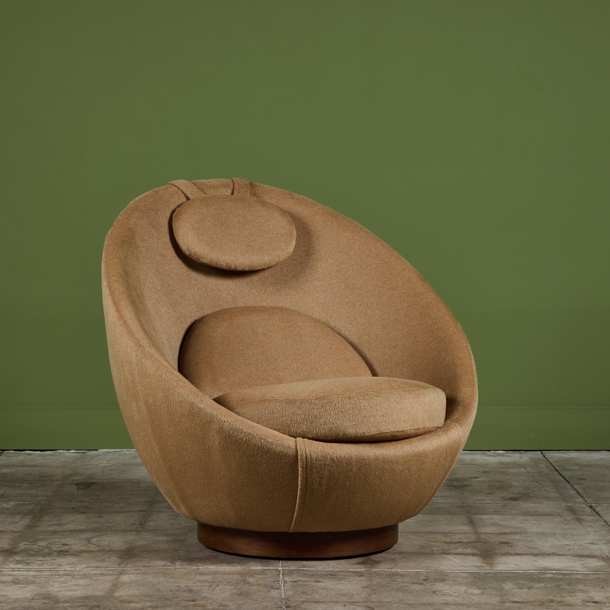 Milo Baughman swivel lounge chair, c.1950, USA. The chair features a rounded back resembling an egg with a deep seat. The chair has three cushions, at the seat, back rest and head rest. The chair has been newly reupholstered in a tan mohair fabric