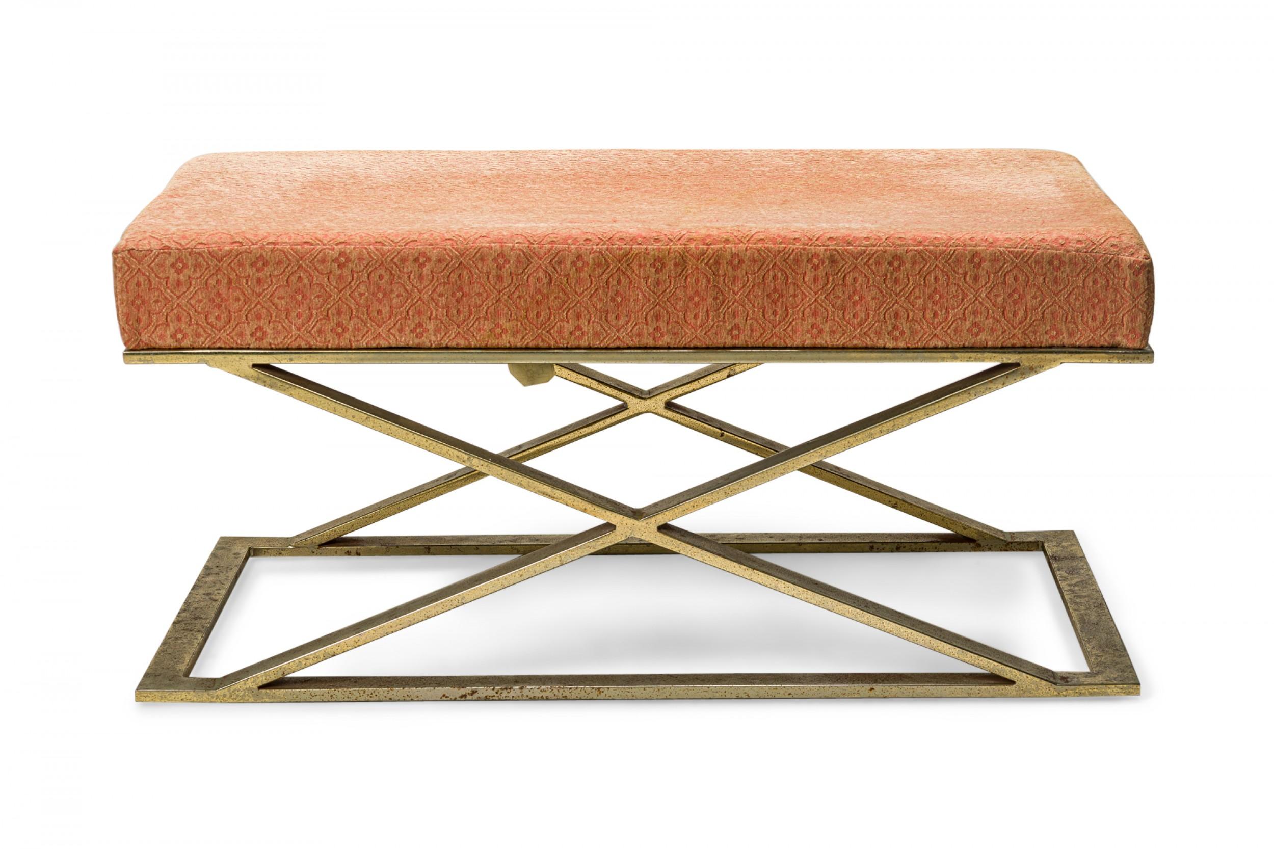 American mid-century bench with a pink tessellated floral pattern fabric upholstered seat resting on a brass X-form base. (MILO BAUGHMAN / THAYER COGGIN)