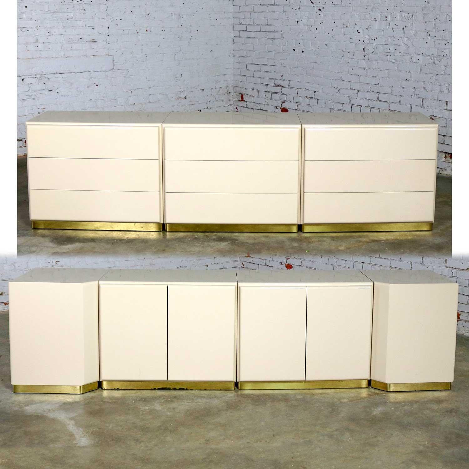 Handsome set of five ivory lacquered cabinets and two corner units on brass over wood bases designed by Milo Baughman for Thayer Coggin. They are all in wonderful original vintage condition. They are not without imperfections but nothing major.