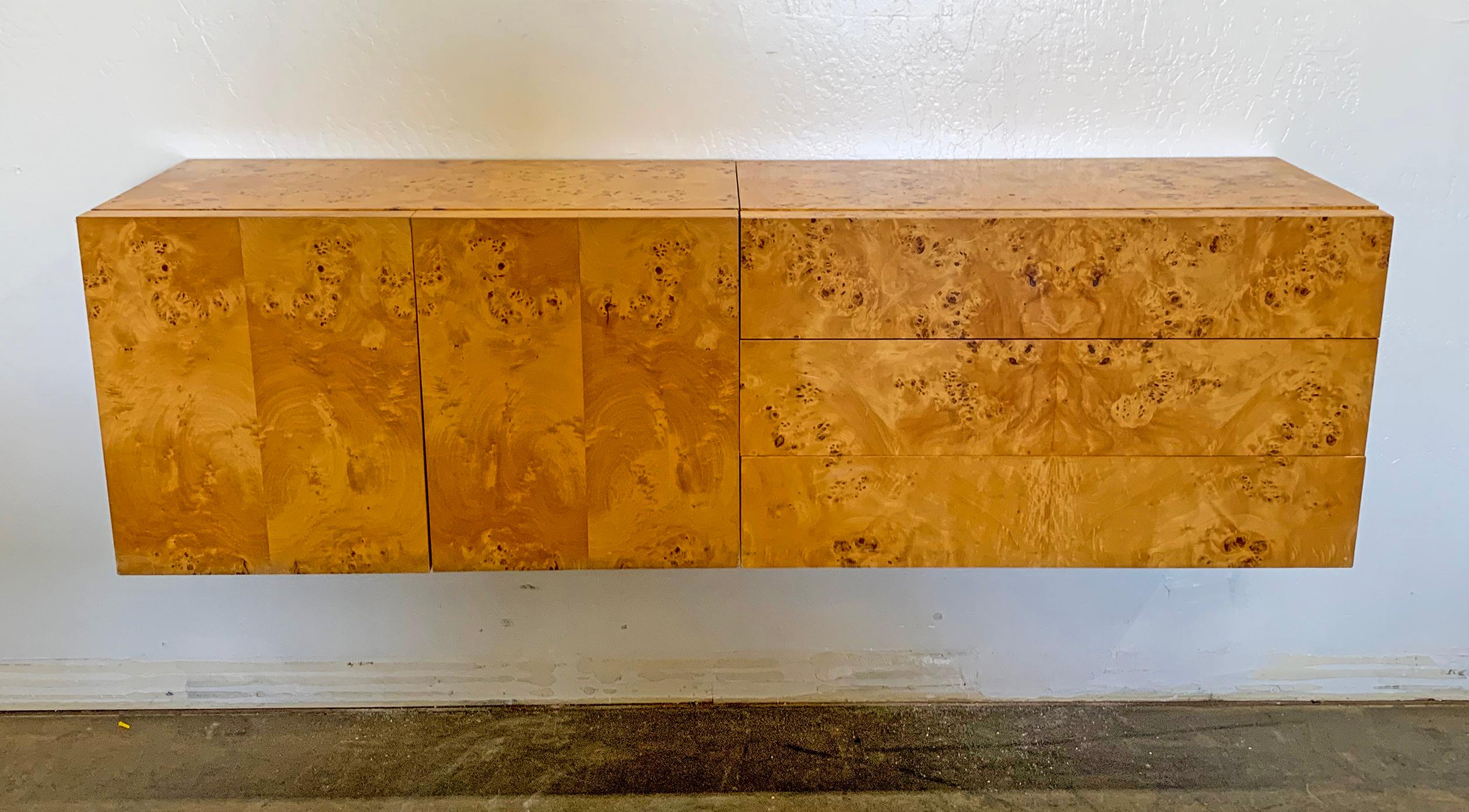This two-piece Milo Baughman style burl wood credenza is simply divine! Using French cleats, this wall mounted credenza is bound to bring a touch of warmth and modernism to any environment. The olive burl grain is wrapped around the top and sides to