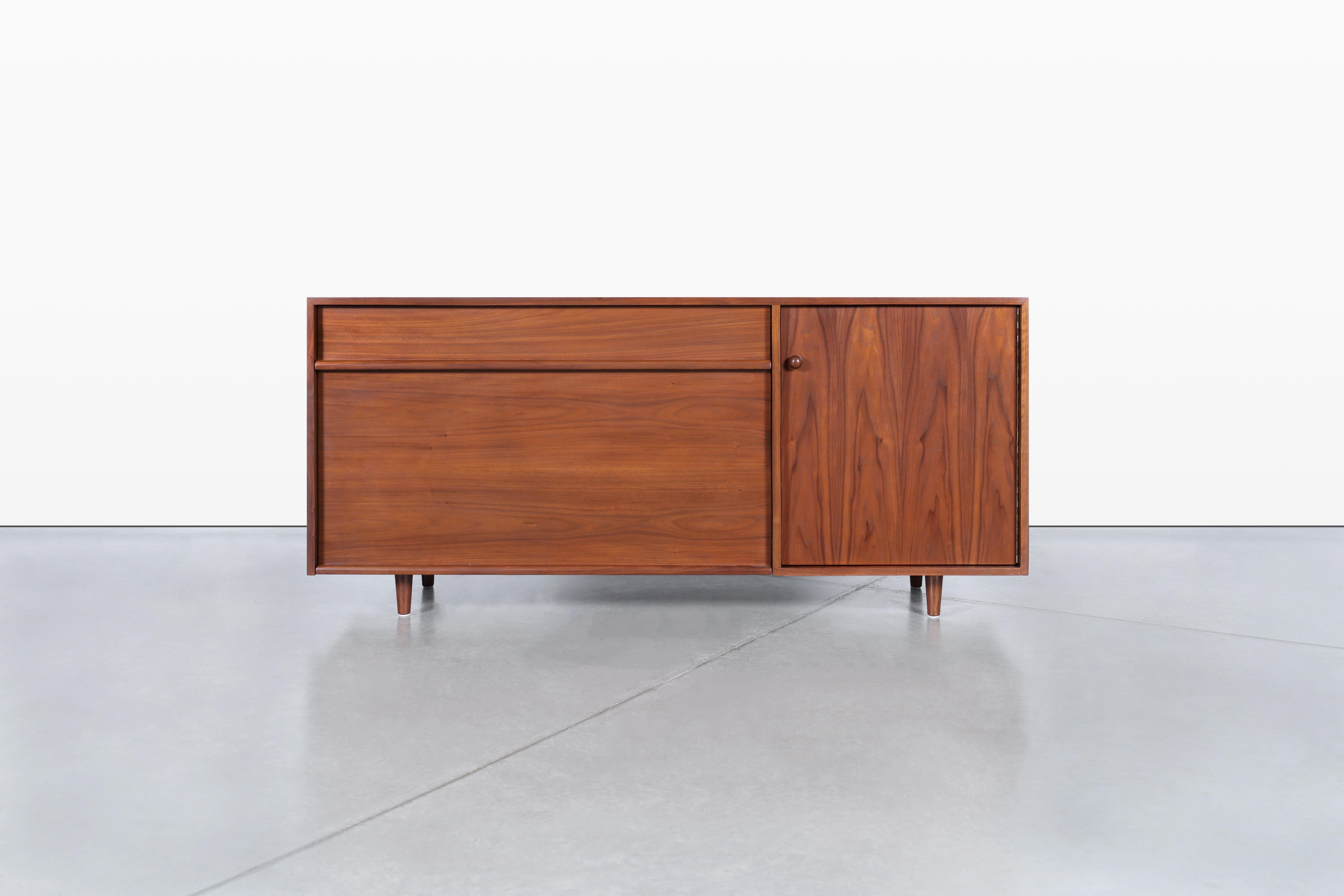 Ti presentiamo una splendida credenza in noce di metà secolo, disegnata dal famoso Milo Baughman per Glenn of California negli anni Cinquanta. Questo pezzo eccezionale, noto come modello 1632, è sia una prima produzione che un reperto raro, il che