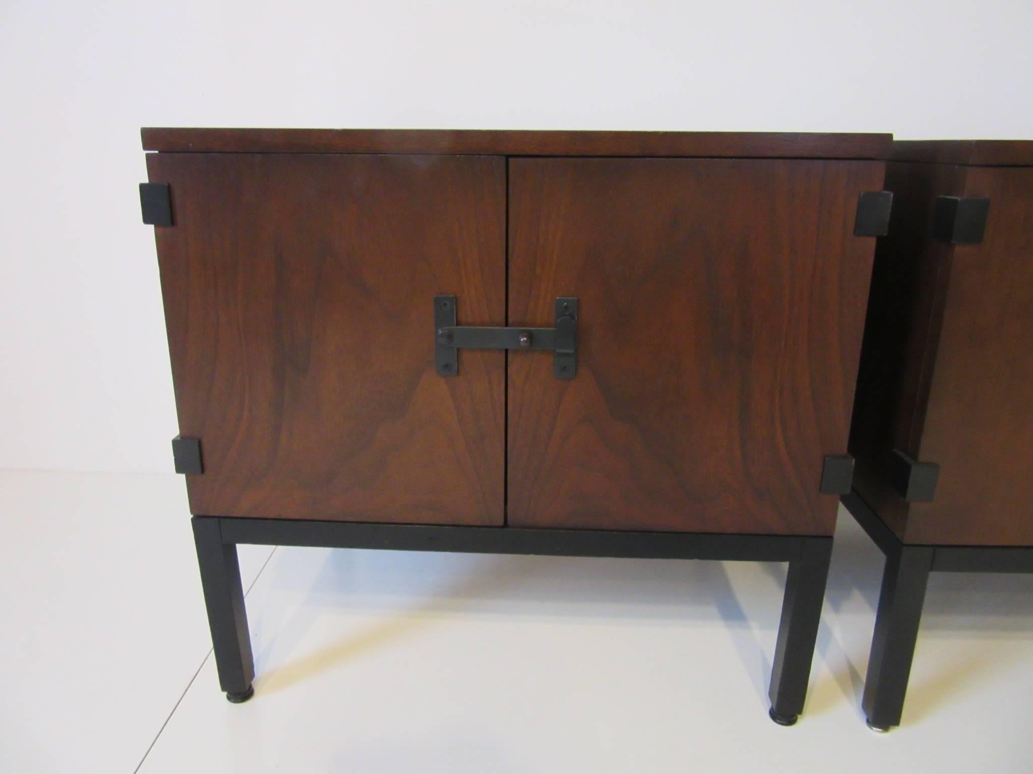 A pair of dark walnut nightstands with double doors and open storage, satin black hardware and leg frames detail the piece, manufactured by the Directional furniture Company.