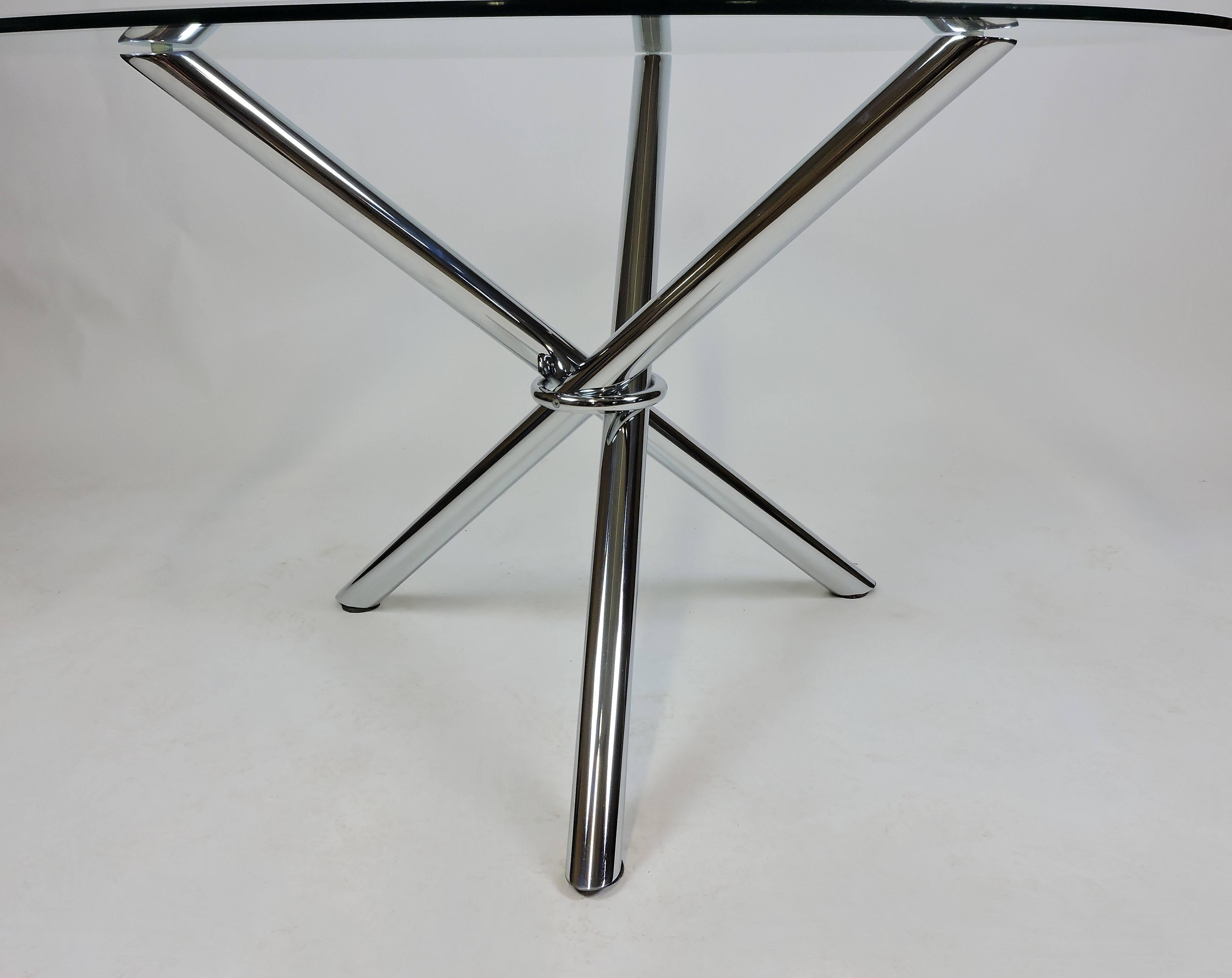 Very cool dining table reminiscent of the Jax coffee table by Milo Baughman. This table has a tripod tubular chrome base with a circular bevelled half-inch thick glass top. Seats four comfortably. Would also make a striking centre hall table.
