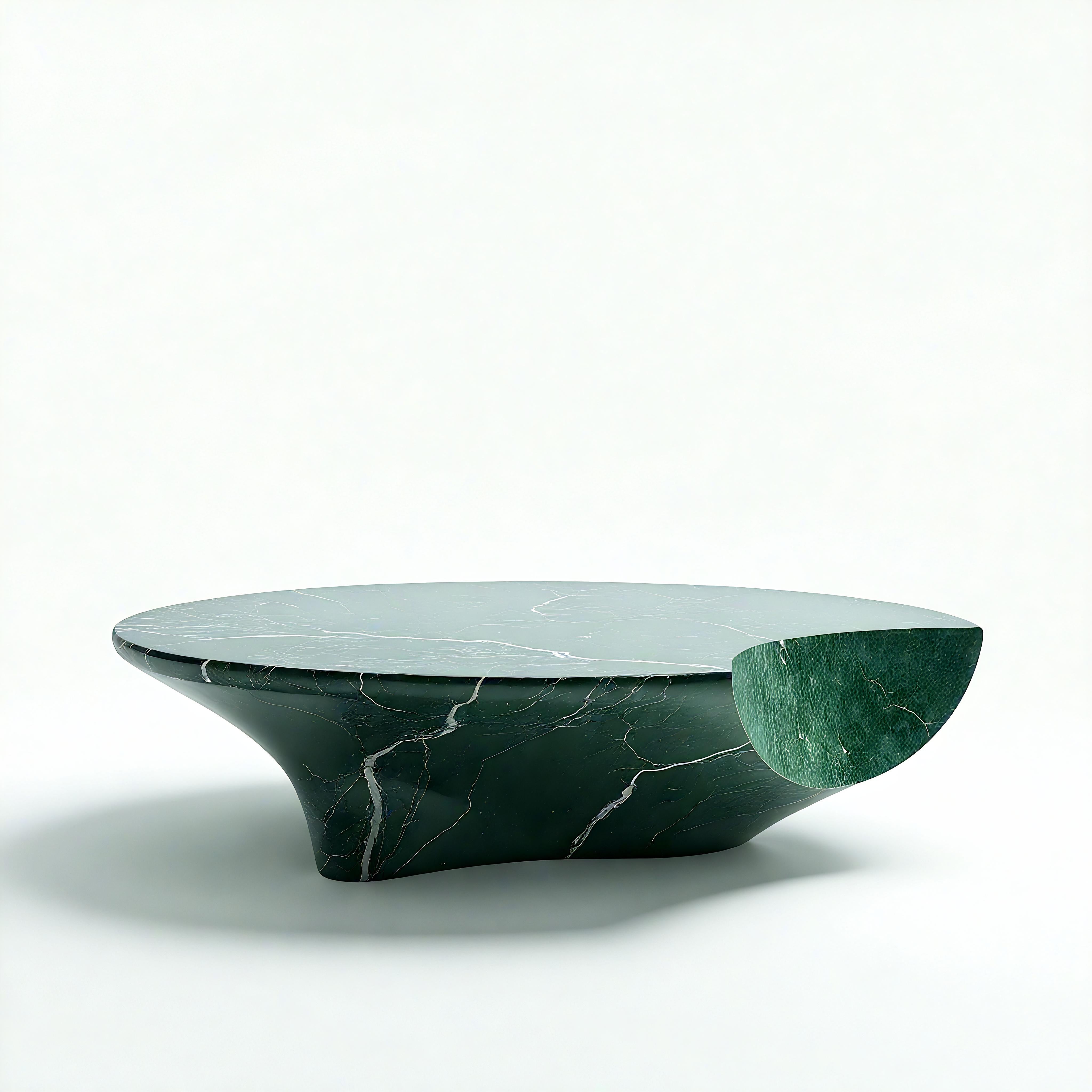 Equilibrio poético de simetría y sorpresa, esta escultural mesa de centro de mármol verde presenta una forma dinámica puntuada por un elemento asimétrico en forma de media luna. Elaborada con mármol Verde Alpi seleccionado a mano, la base suavemente