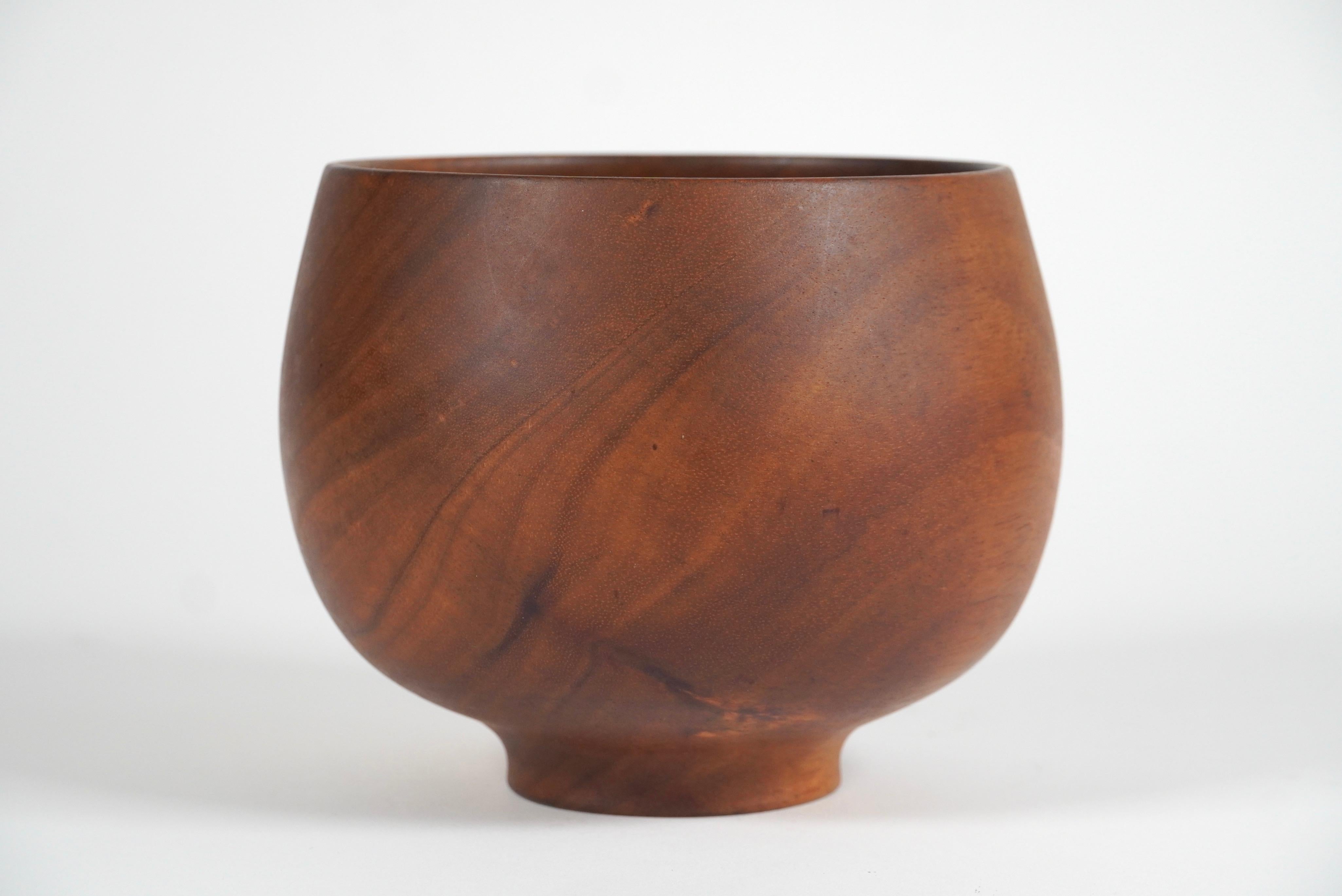 Calabash Milo turned wood bowl by craftsman Jack Straka (1934-) of Hawai'i. A footed form with a bulbous bottom curving into a thin walled tapered bowl, beautiful graining with dark and golden hues across the bowl. Marked with ink stamp on the