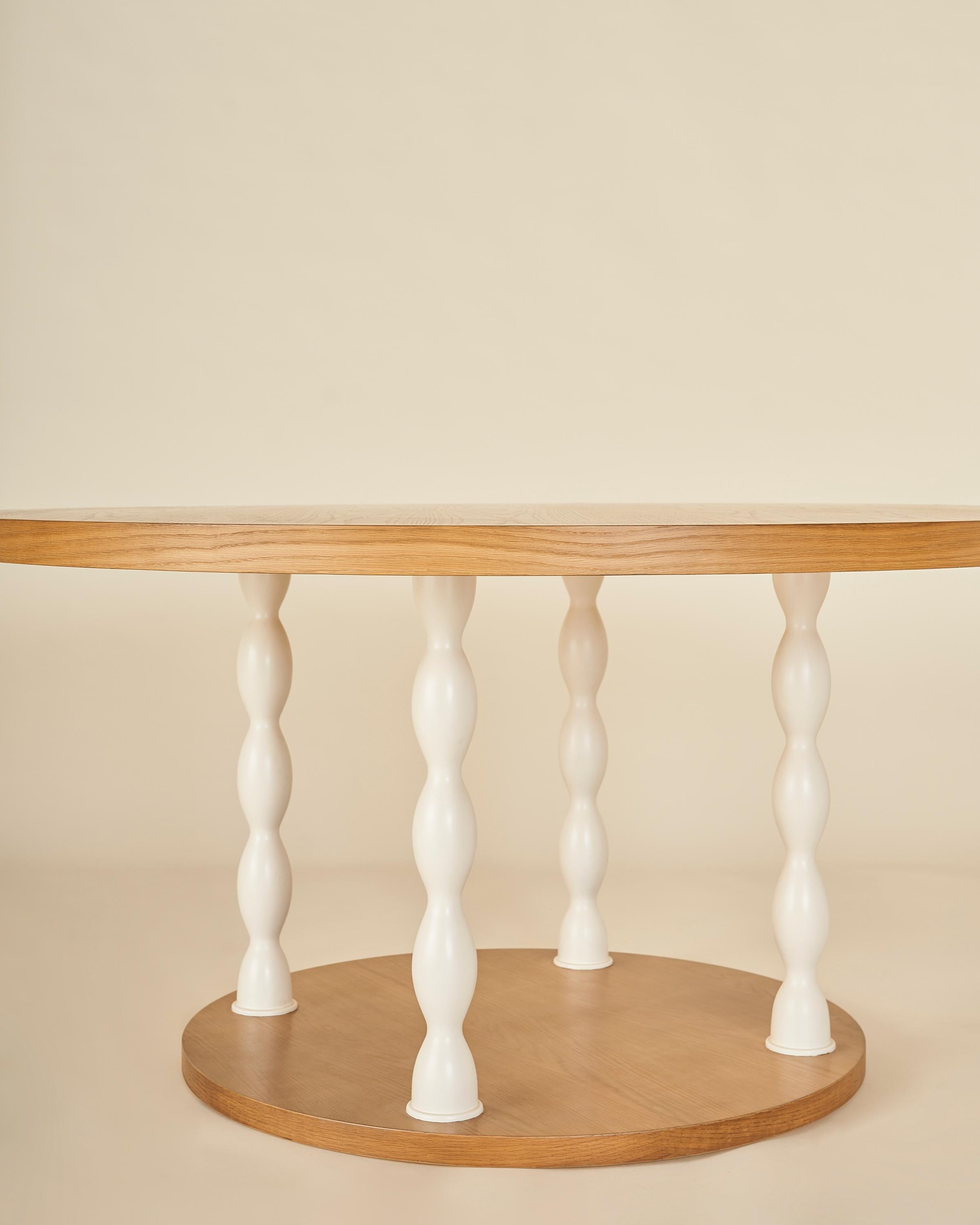 A classic and casual round dining or library table with a solid oak top that rests on four off-white lacquer legs with undulating curves and solid oak base.

Our collection pays homage to the everlasting idea of home, a place that is alive as its