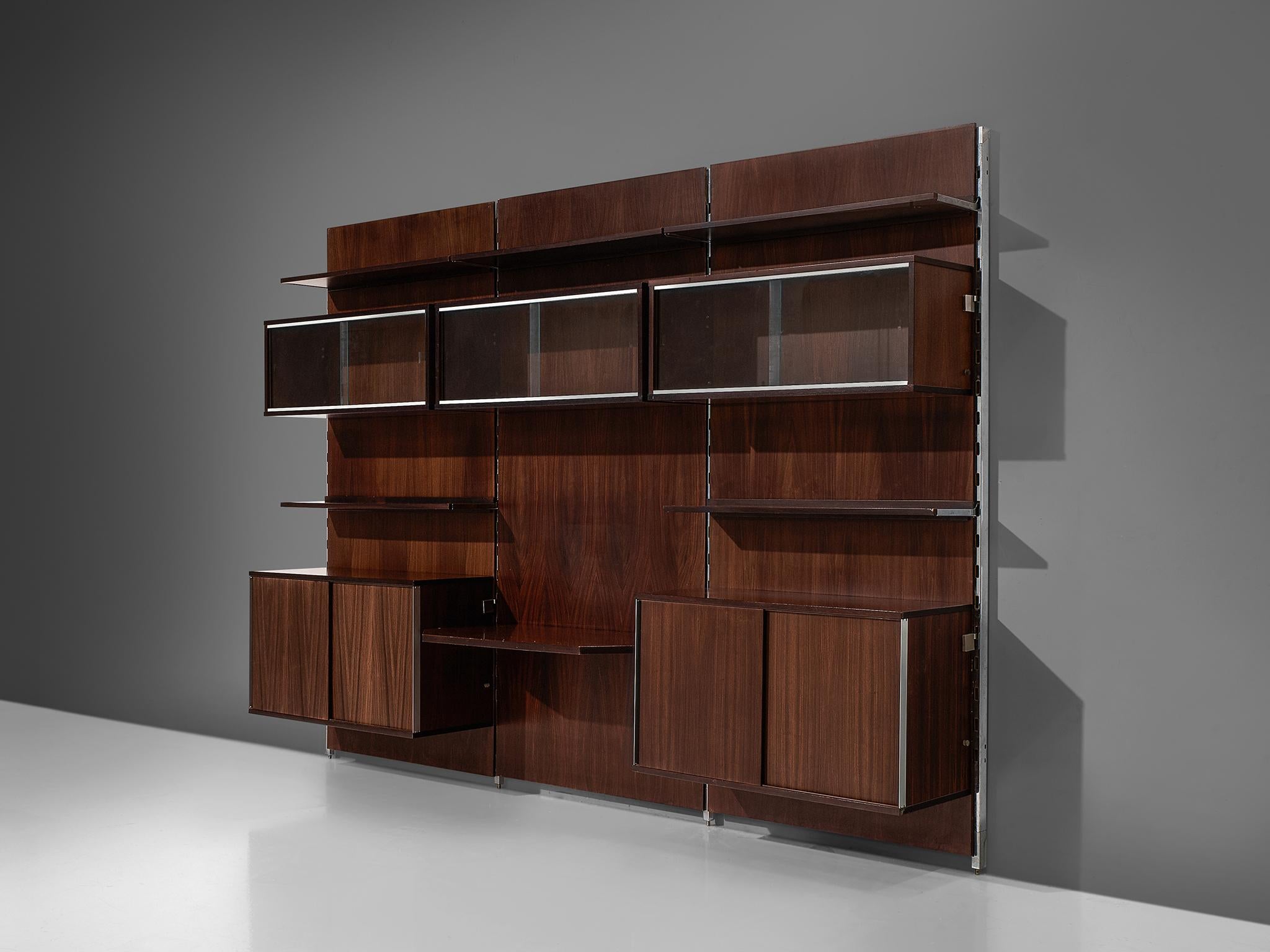 MIM Roma, cabinet, rosewood and metal, Italy, 1960s.

The monumental wall-mounted cabinet consists of four wall panels with various different storage facilities. The finish and details of this shelving wall unit are of a high standard. The piece