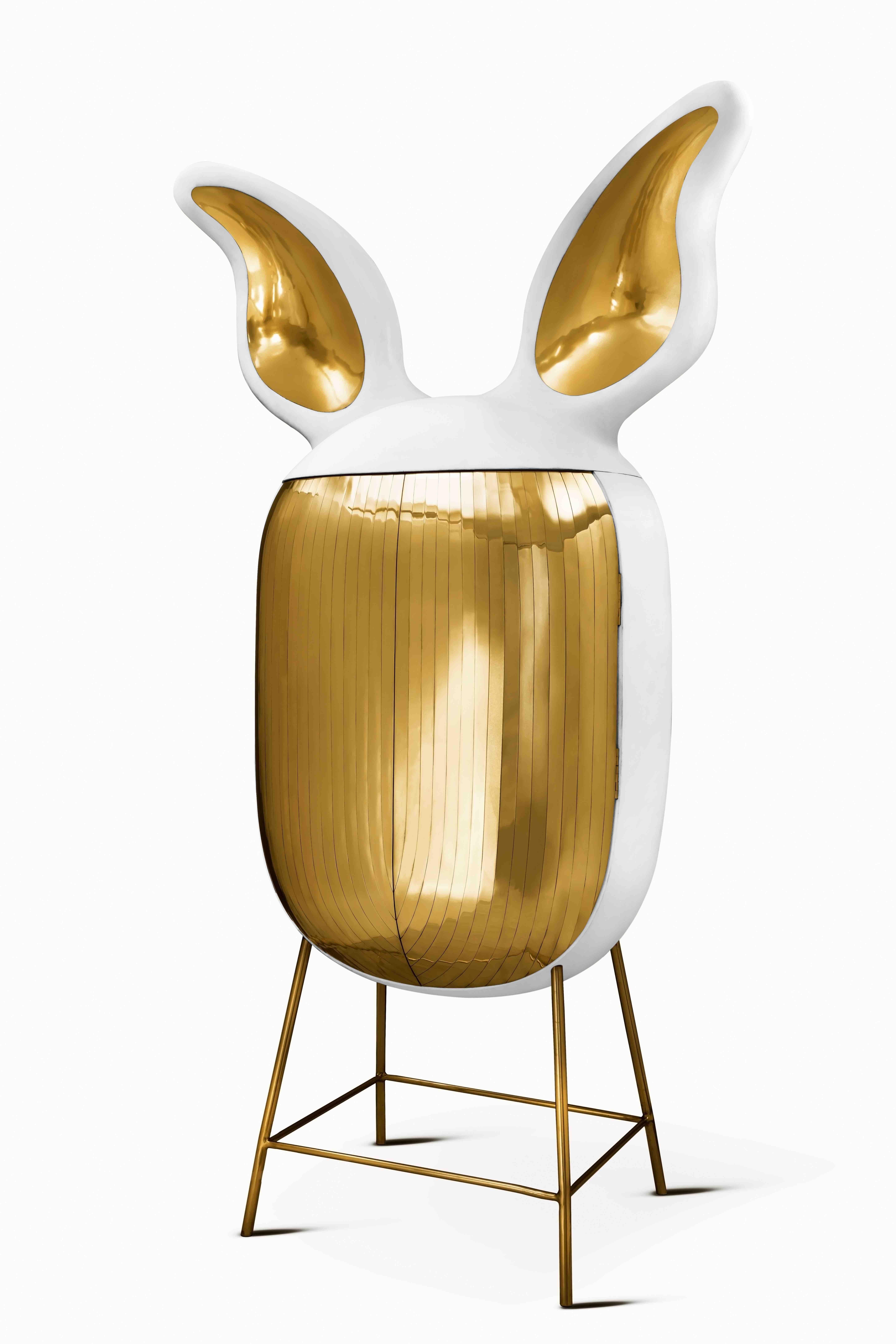 Il mobile bar Mimi con intarsi in ottone di Matteo Cibic è un mobile bianco con orecchie giganti e gambe alte e delicate. Le finiture in ottone aggiungono opulenza. Un pezzo affascinante da inserire in qualsiasi spazio interno.

