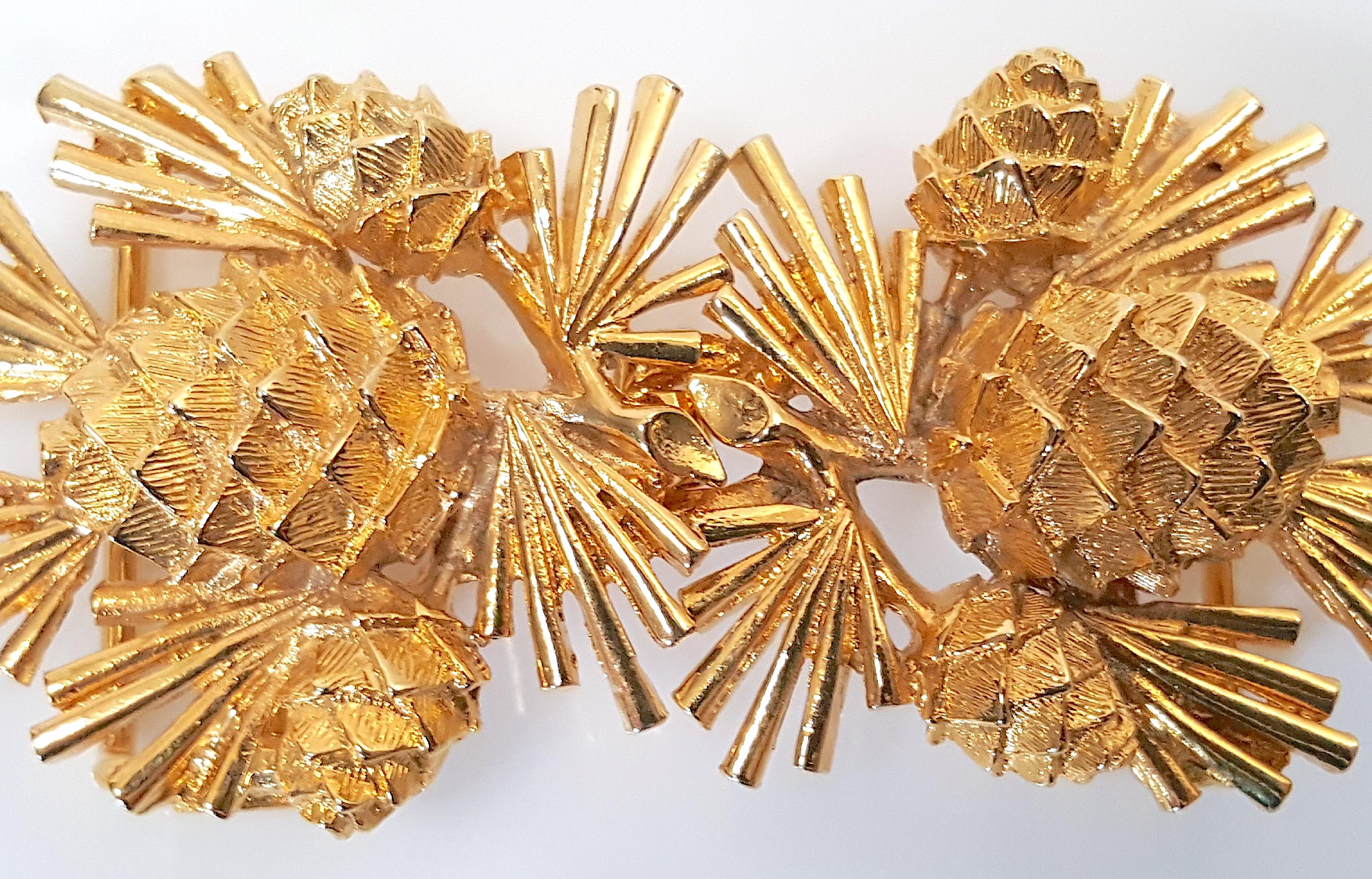This curvilinear textural gold-gilt metal two-piece belt buckle or convertible pendant depicting pine cone and needle sprays was designed by Mimi di N in 1981, as noted in the signed dated stamp on each piece. The eye-fastening piece of the