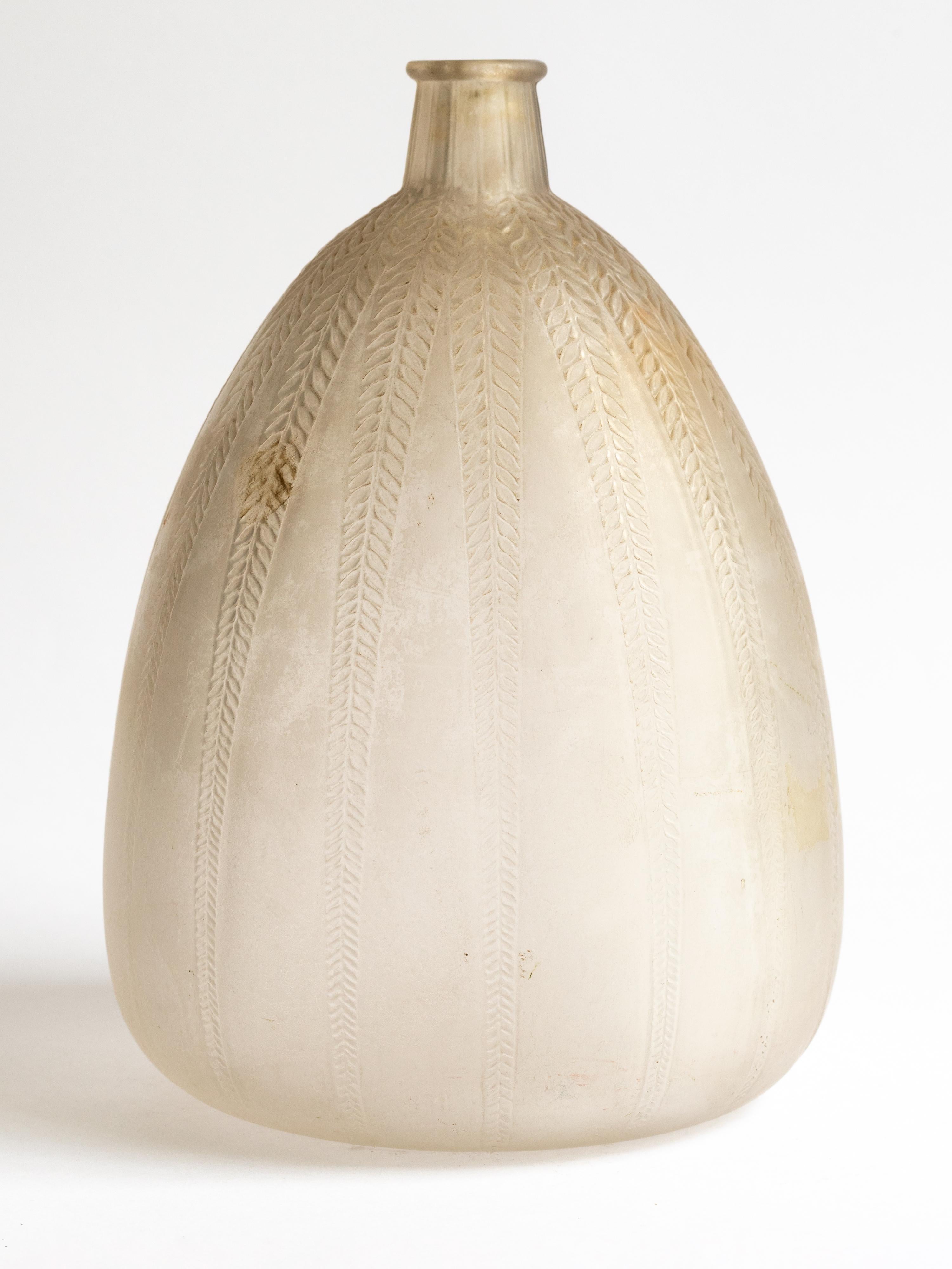 René Lalique, dreieckige Form, umlaufendes, nach unten gerichtetes, vertikal angeordnetes, sich wiederholendes Blattmotiv aus mattiertem und patiniertem Glas.
Vase unter einem kurzen und schmalen Hals. 

Geformte Marke R.Lalique.

Bibliographie: