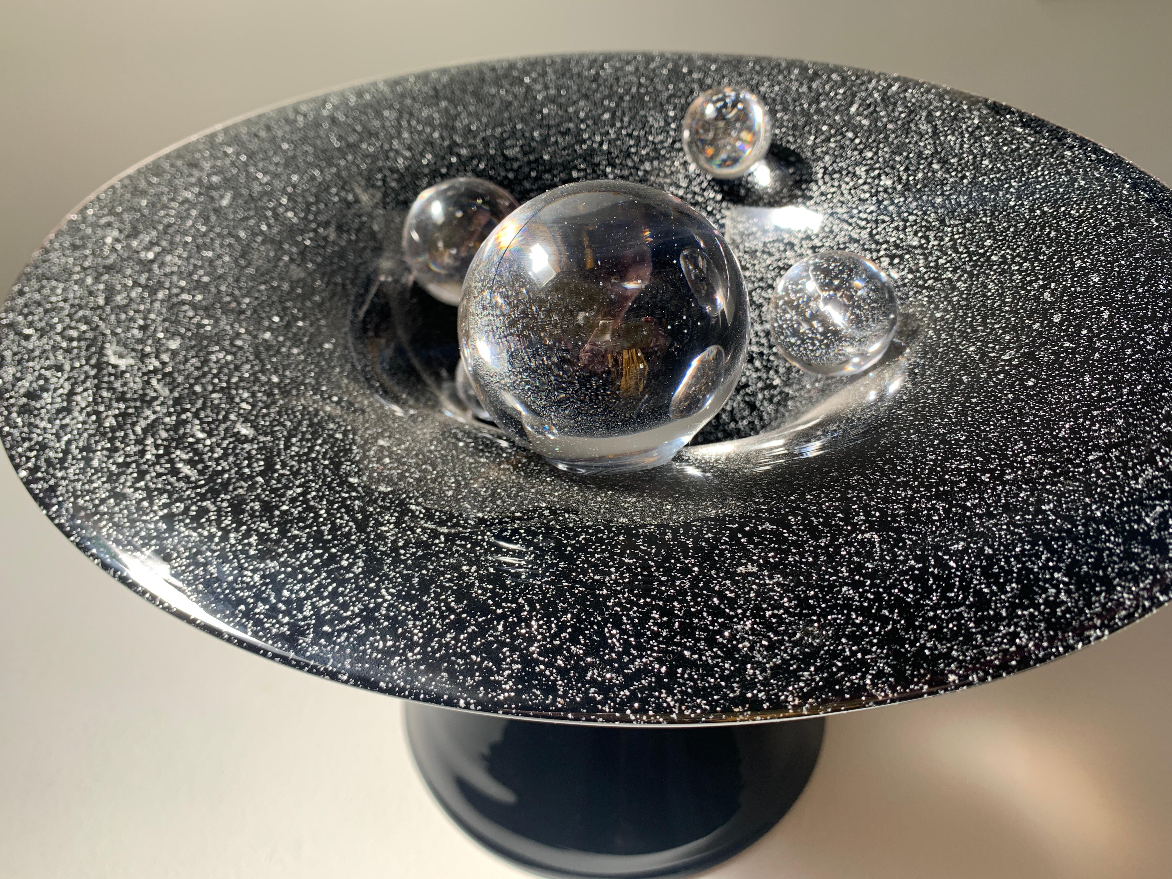 Questa bellissima scultura in vetro soffiato a mano di Minami Oya infonde delle macchioline di mica nel vetro nero per aggiungere scintille ed evocare le stelle dell'universo.

Minami Oya è un'artista visiva, una vetrinista e un'educatrice che