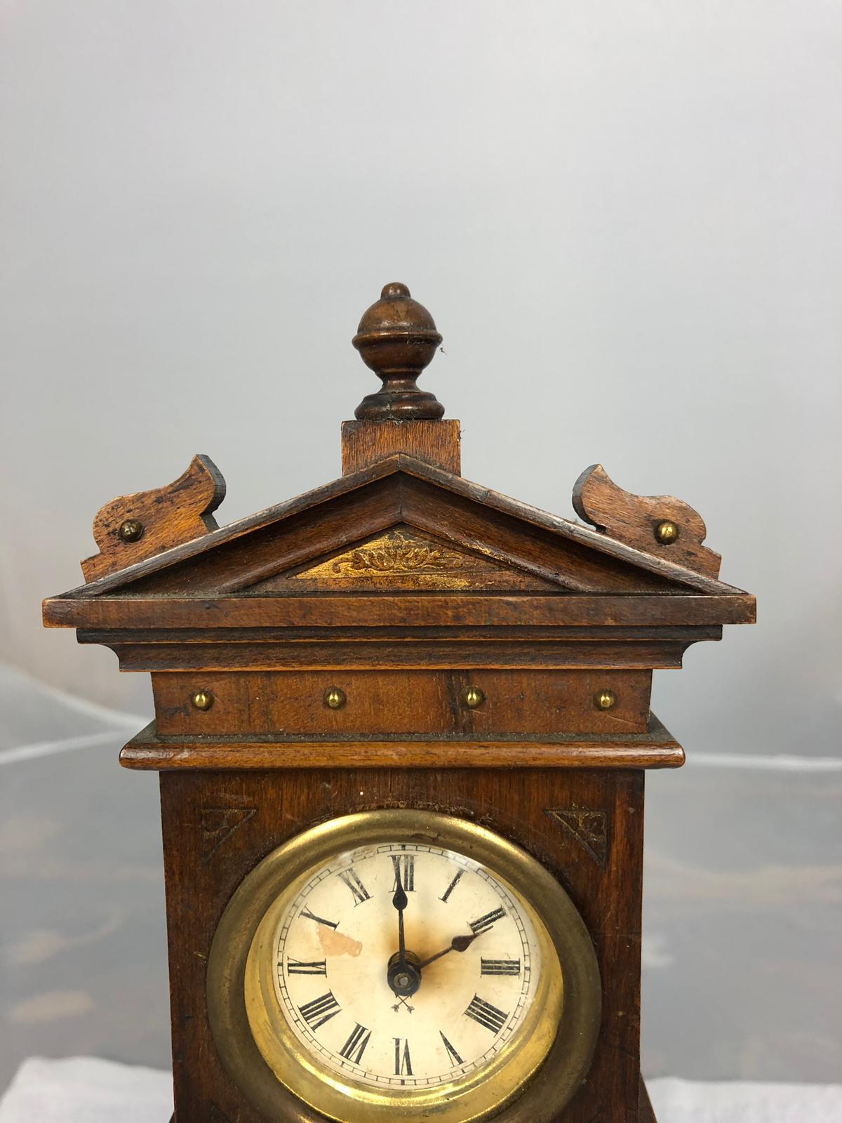 A 19th century, miniature and wooden carved grandfather clock, with a carved wooden floral centre, and a roman numerical face, typical of the English clock design.