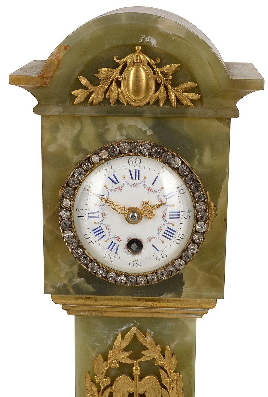 An unusual late 19th Century French minature gilded ormolu and carved Onyx mantle clock, in the style of a Louis XVI longcase clock. Having an enamel clock face and classical mounts.
 
Batch 65 CHEYN 57005.