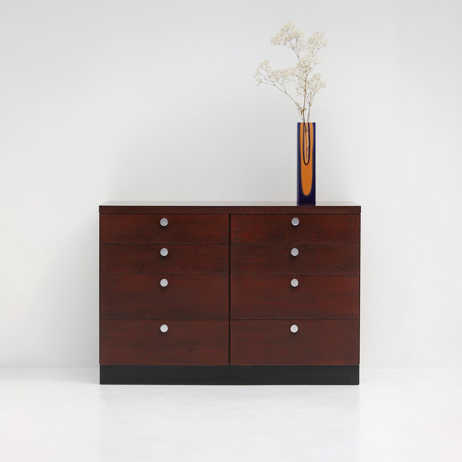 This decorative commode can be a nice fit to your living- or bedroom. It has 8 drawers each detailed with an aluminum knob. The red/brown color of the wood brings gives a warm and cozy feel to this piece of furniture. Produced by Belform in the 70s,