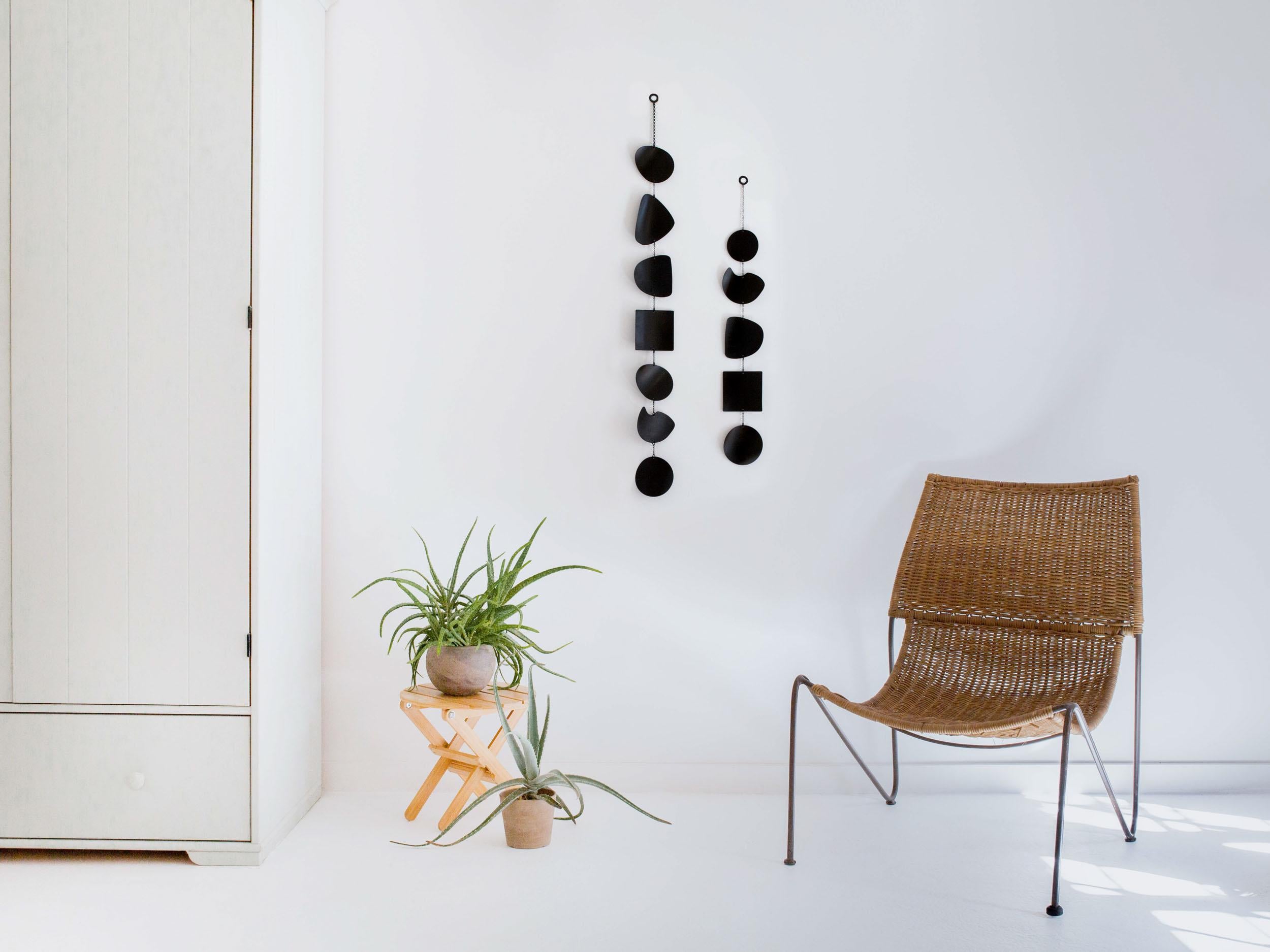 The Mineral wall hanging draws inspiration from the worn shapes of river rocks. The organic curved shapes and striking black patina finish create inviting dimension. Ideal for narrow spaces, this smaller vertical piece can also be hung with the