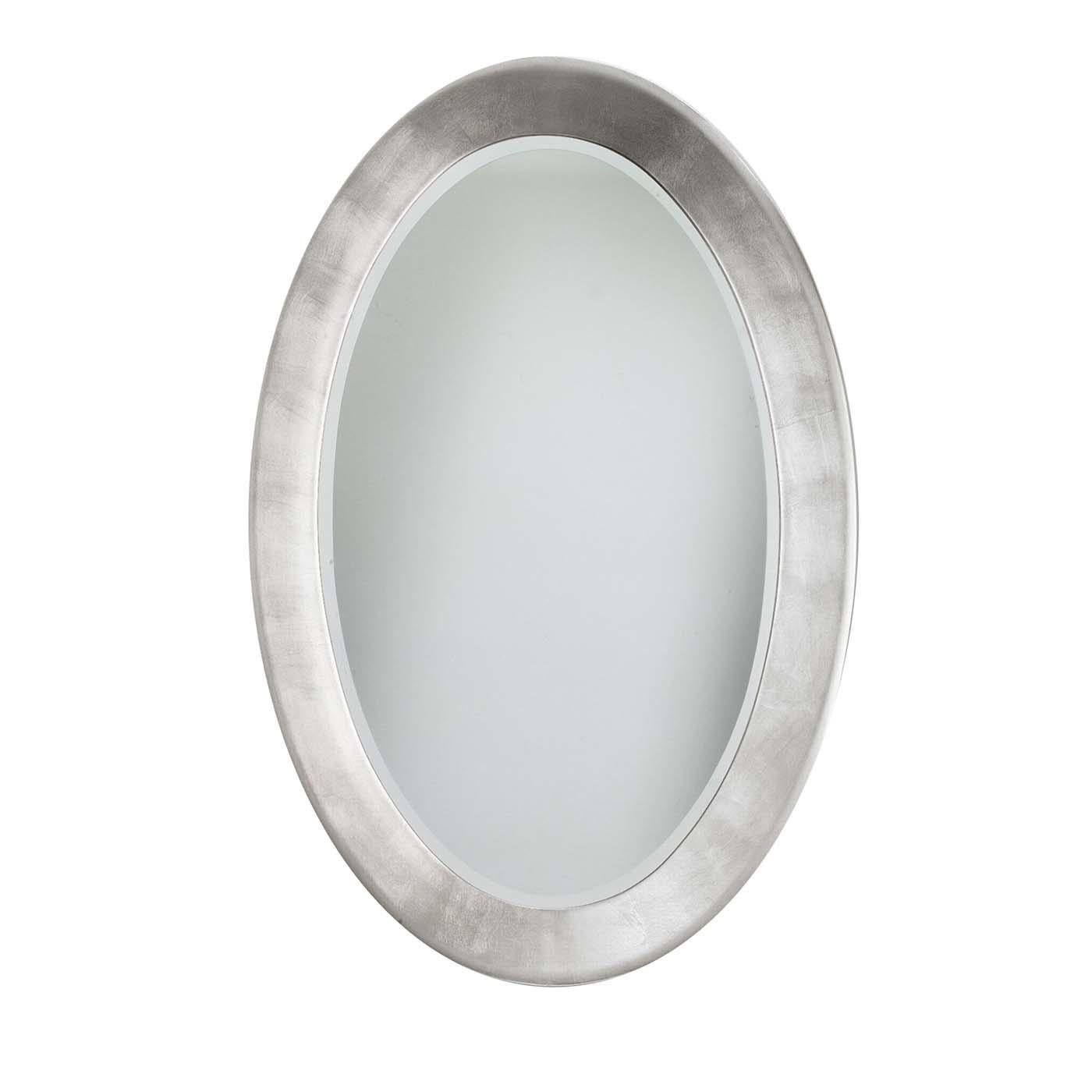 Essential and glamorous, this exquisite wall mirror displays an oval silhouette comprising a reflecting surface in Italian crystal. The wooden frame (10 cm wide and 3.5 cm thick) showcases a bright, hand-applied silver leaf coating and encompasses