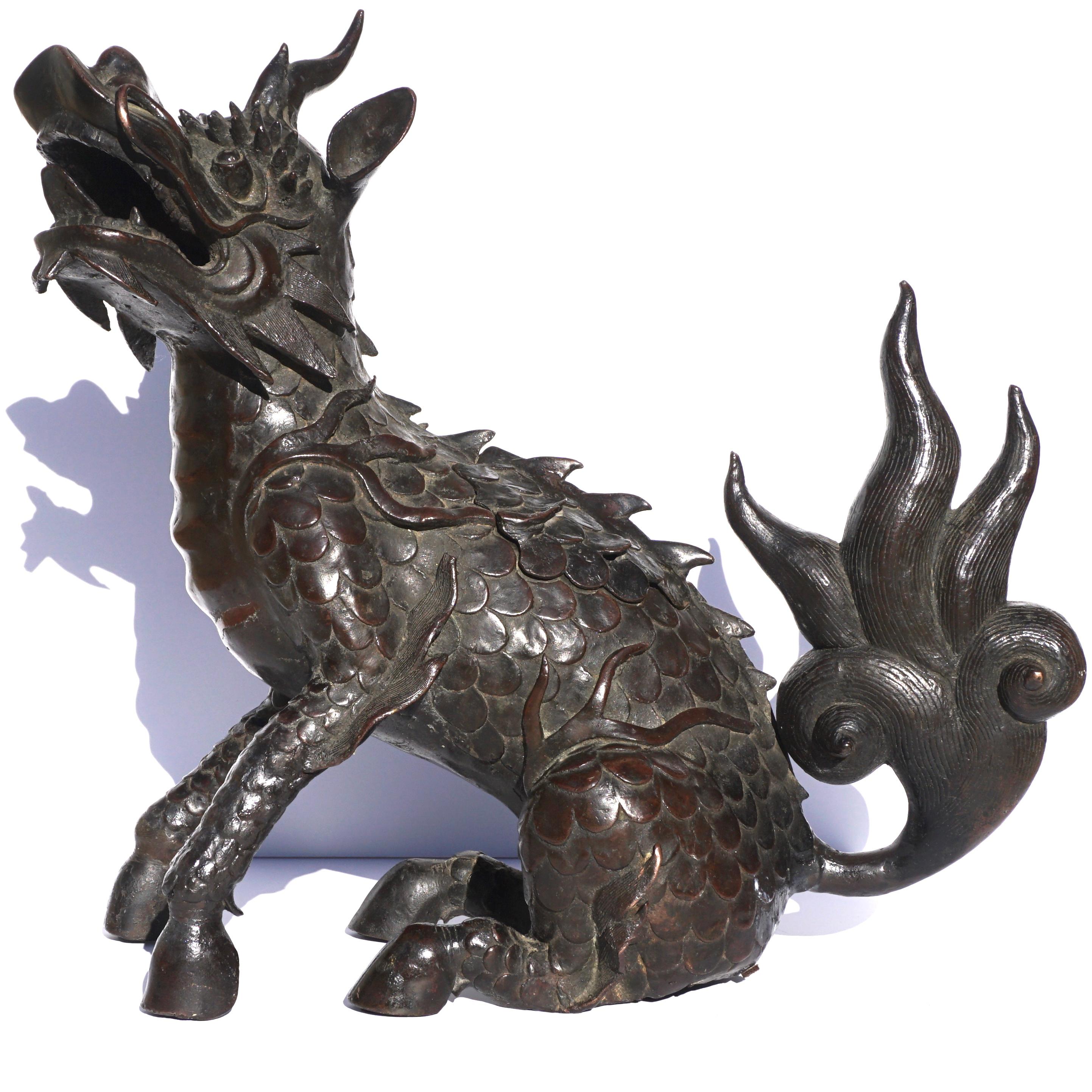 A large Chinese Ming bronze kyrin shape incense burner. Beautiful and decorative period Ming dynasty cast bronze of a scaled foo dog or mythical beast with horn, whiskers and teeth. The feet are hooves, its dragon head with a single horn and mouth