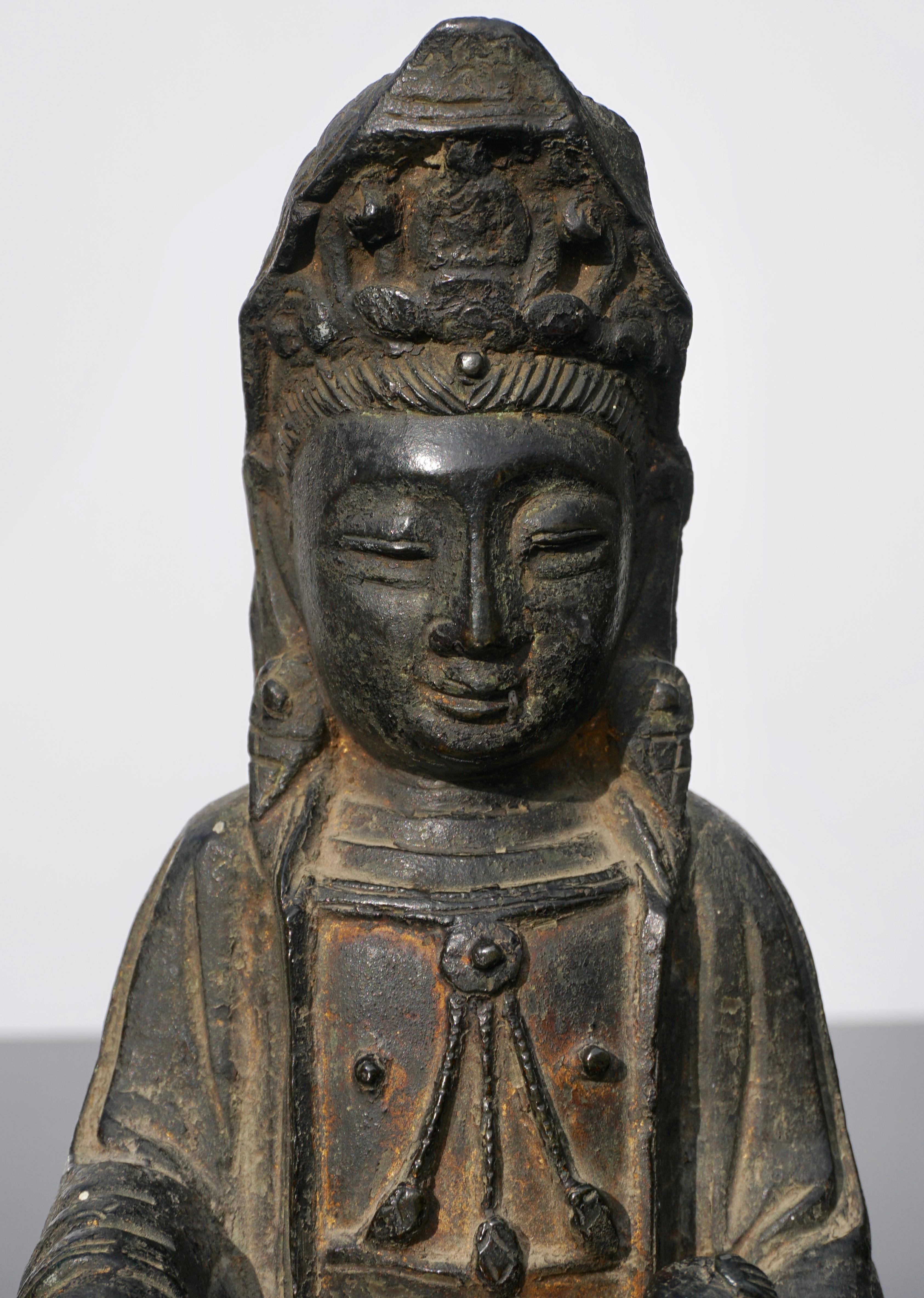 A early Ming dynasty lacquered bronze statue of the feminine Buddha figure; Guanyin with child, circa 15th-16th century China.

The Buddha cast seated with the right leg raised and a child supported on the left lap, wearing a loose fitting robe