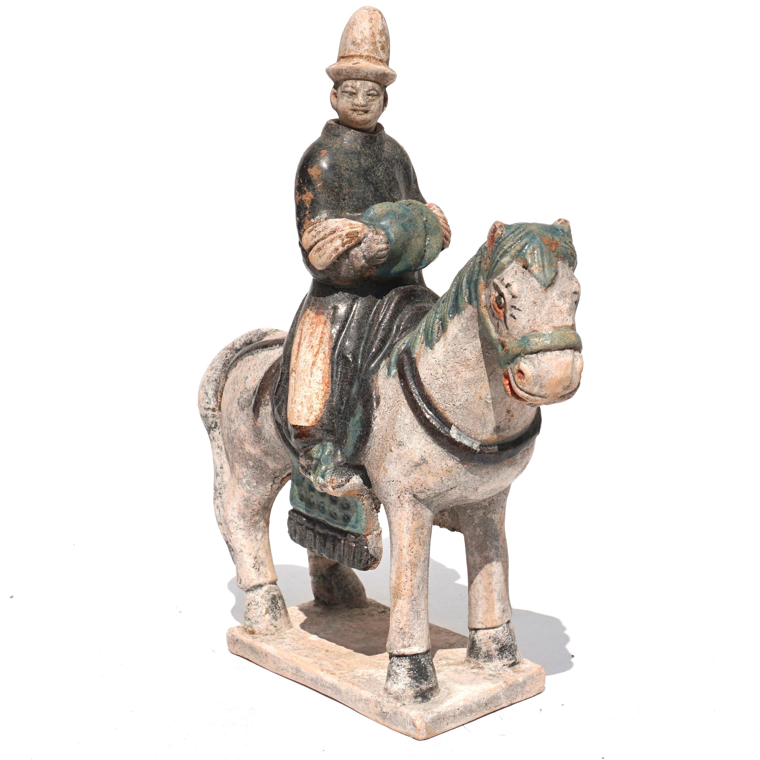 Ca. 1368-1644 AD. Ming Dynasty. 

Ceramic Horse with Rider. An elegant ceramic figurine depicting a grey horse in a standing pose with its neck stretching forward and its tail loose, over one hind quarter. The horseâ€™s trappings, including the