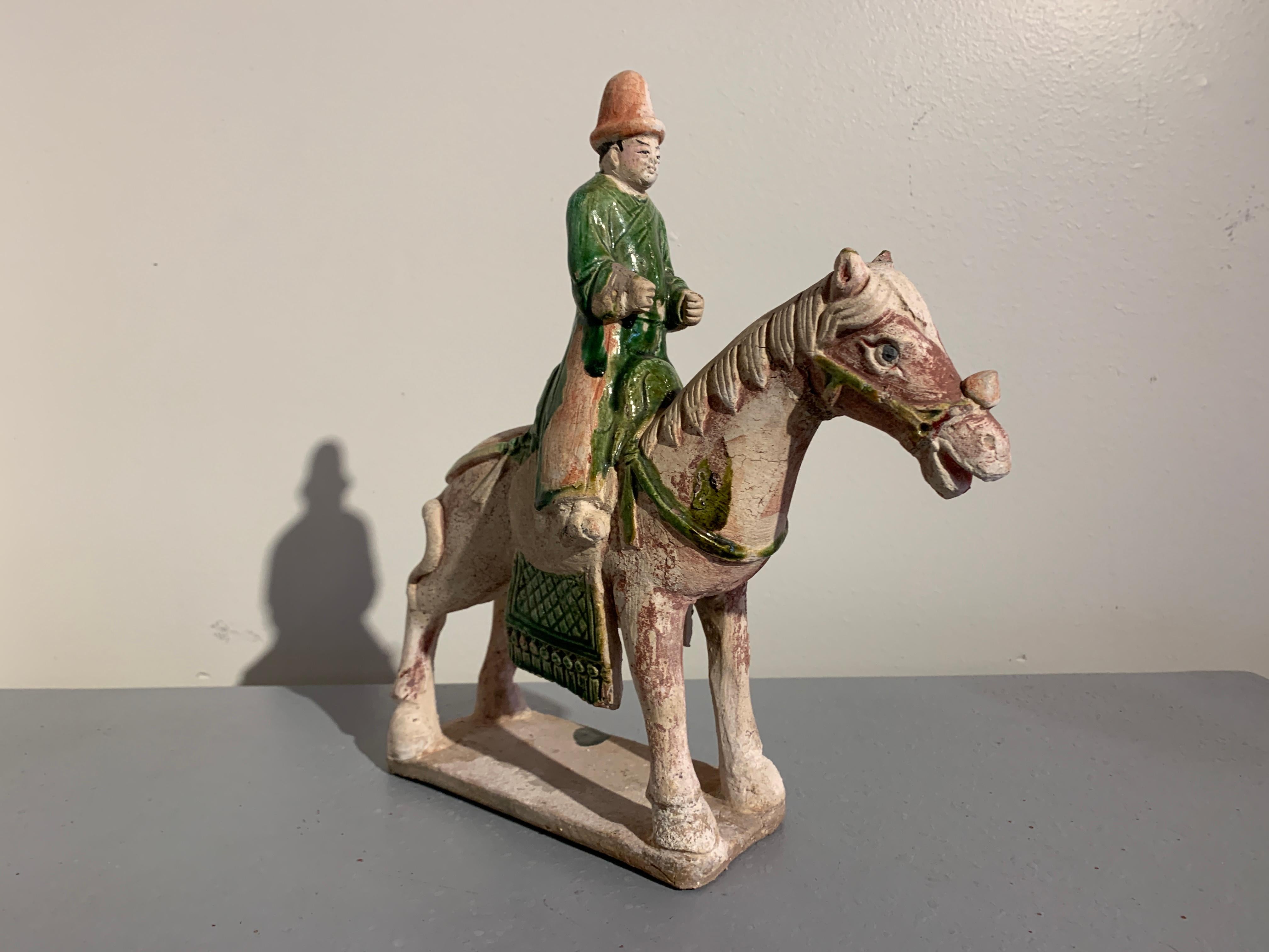 A charming Chinese Ming Dynasty figural group of a horse and rider with an associated attendant, green glazed pottery, Ming Dynasty (1368 to 1644), circa 16th century, China. 

The group comprised of a horse with a mounted rider, and a separate