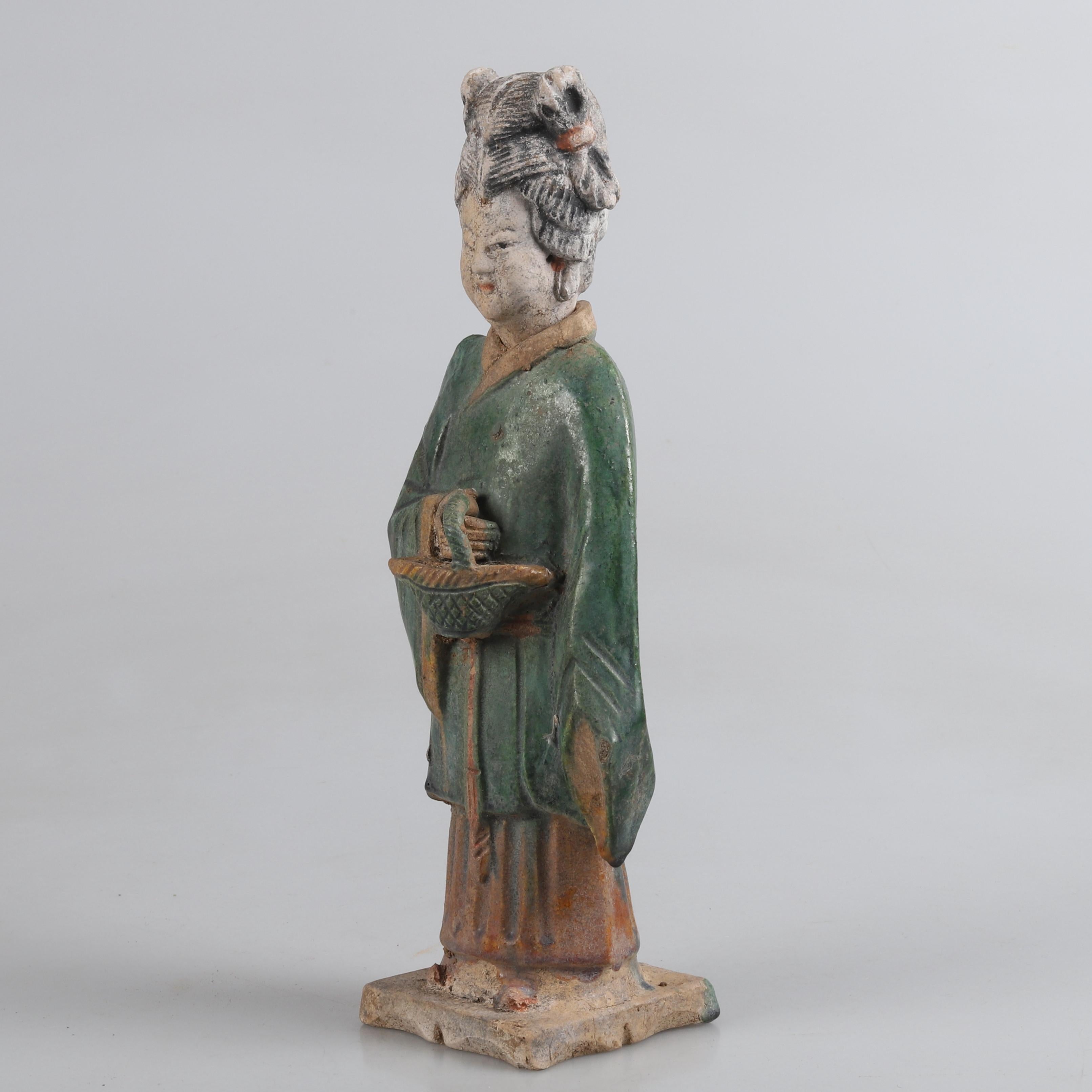 A fine green-glazed Chinese Ming Dynasty earthenware figure. In form of a female funeral guide, glazed and painted in green, yellow, red and black It has been styled in long, flowing robes, colored a vivid green. Additional features have been