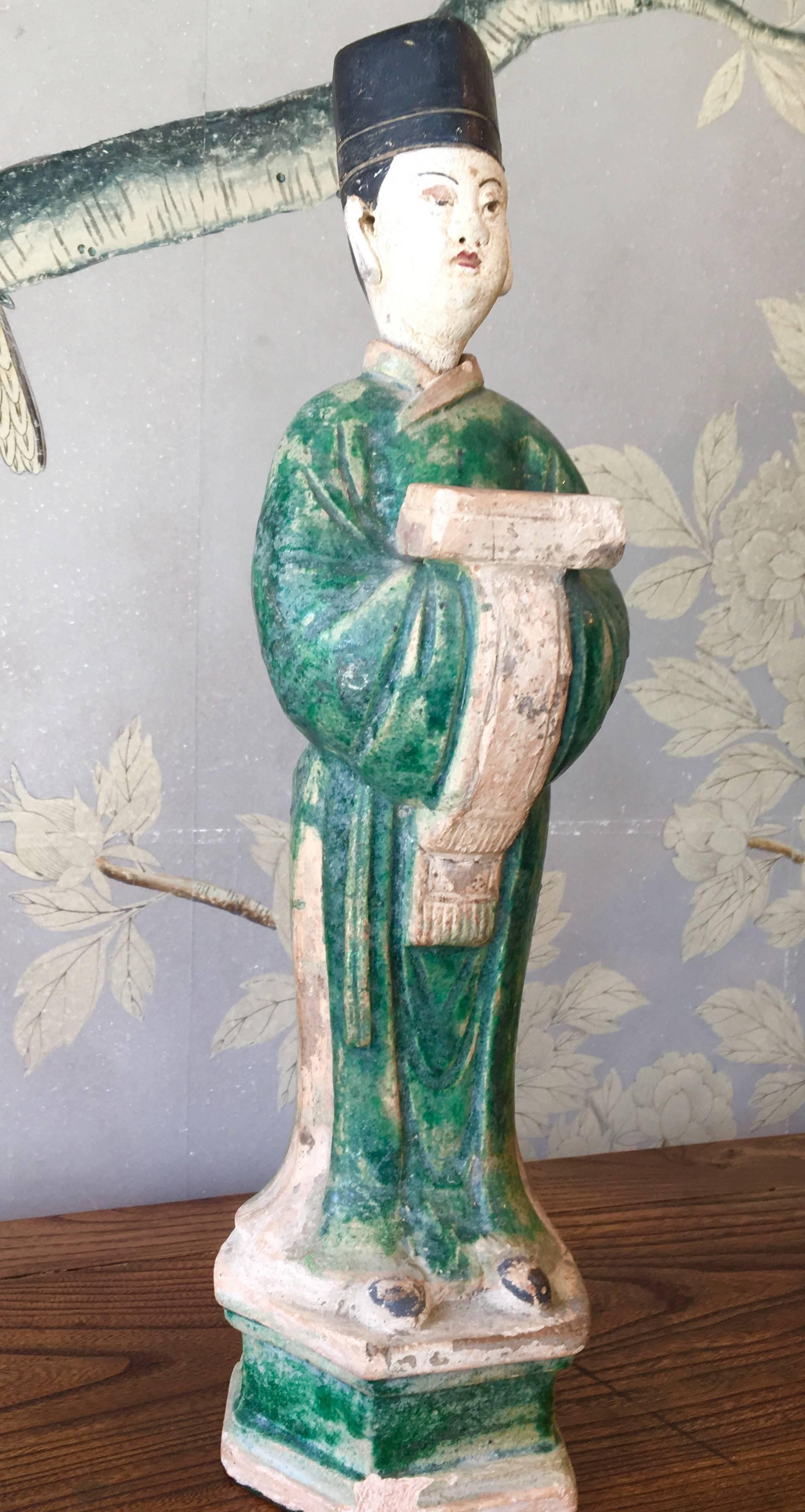A Ming style Chinese pottery figure of an attendant, partially glazed on an attached hexagonal base.