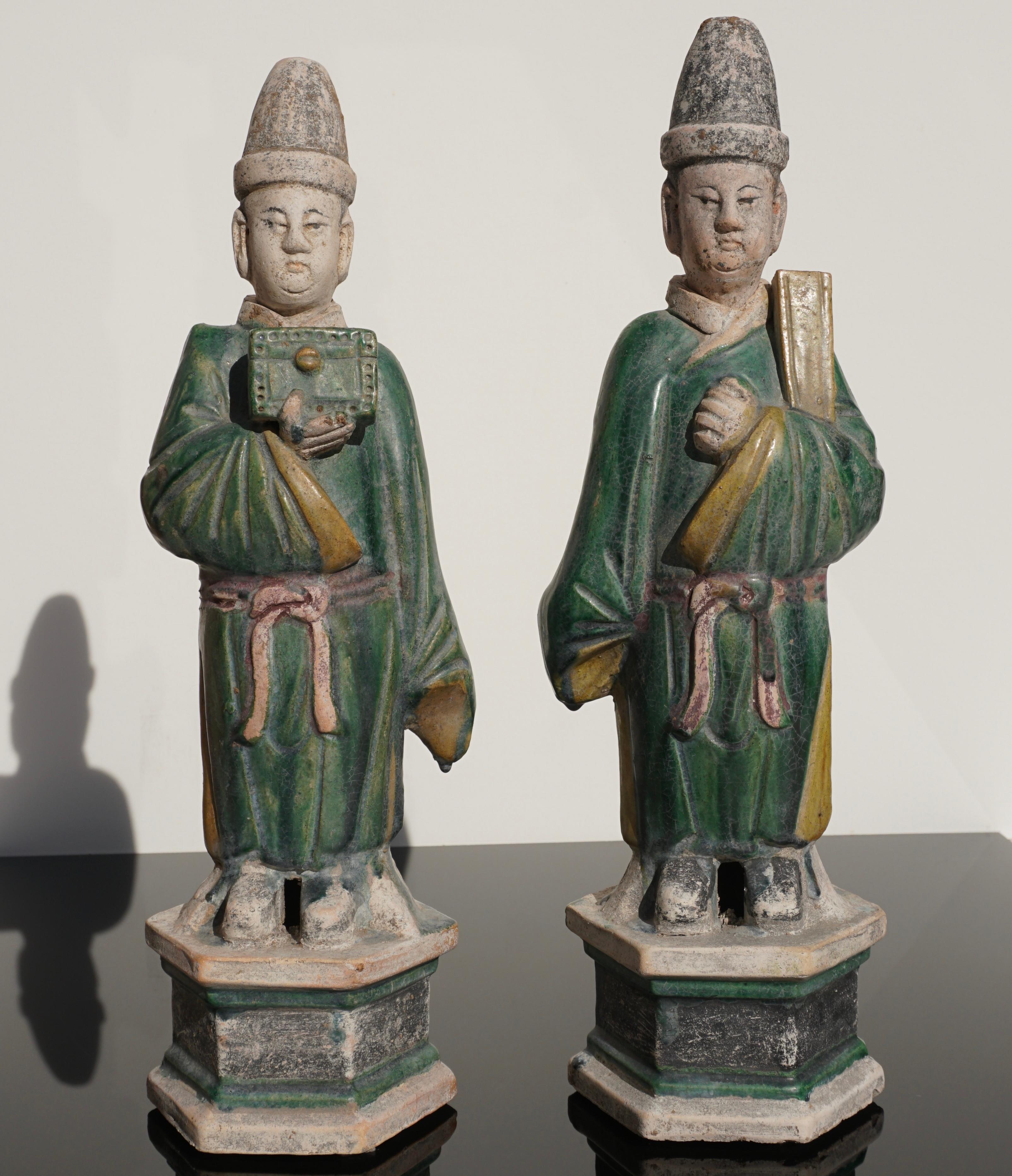 A perfect and large pair of Ming period Terre cotta Dignitary Tomb attendees with green and yellow sancai glaze wearing robes and carrying a chest and manuscripts. Attendees have detachable and interchangeable heads and stand on Hexagon