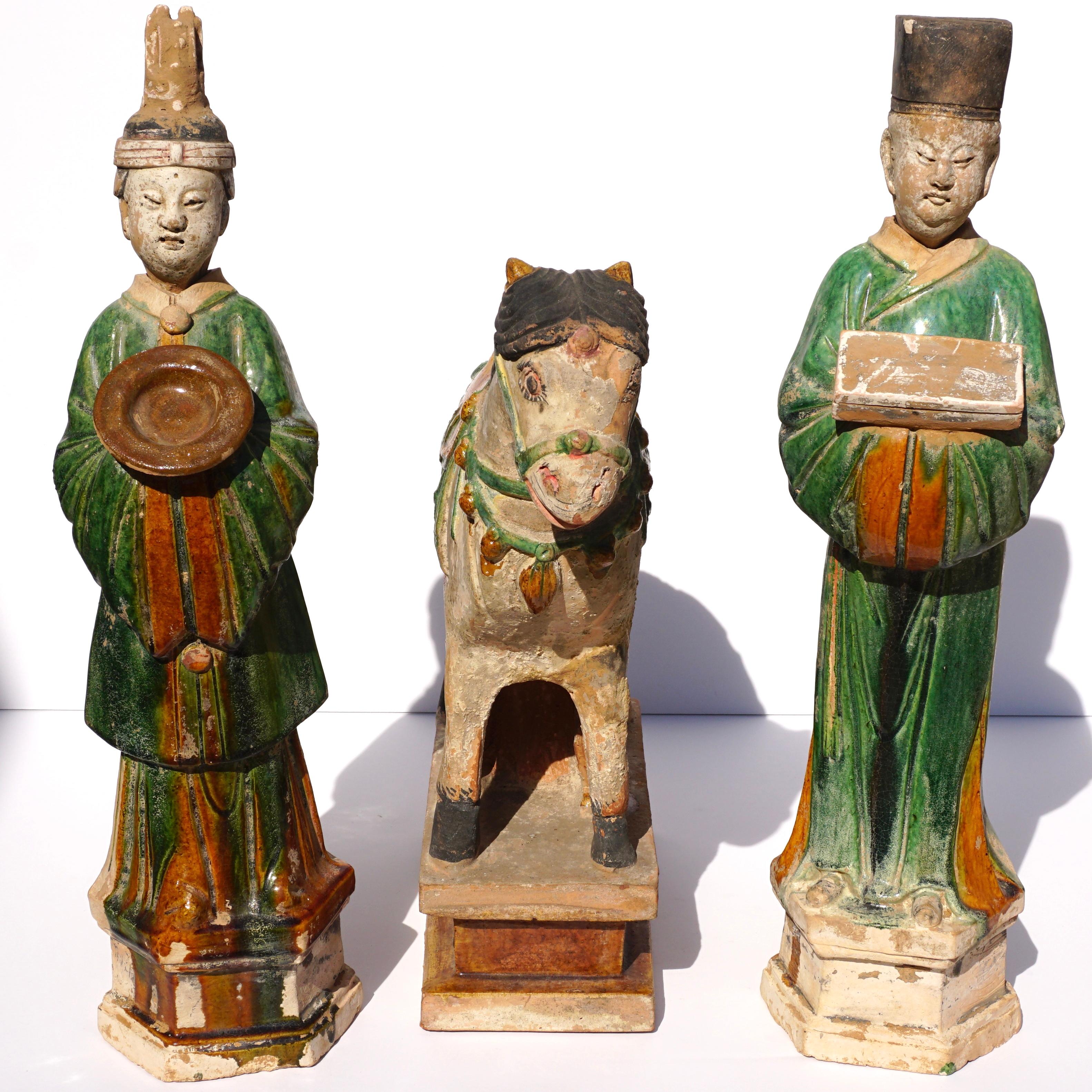 A large a monumental set of pottery Terrecotta tomb figures representing Male and Female dignitaries bearing gifts along with a saddled Horse. All sculptures are Sancai glazed with Signature ming green and brown colors. This particular collection is