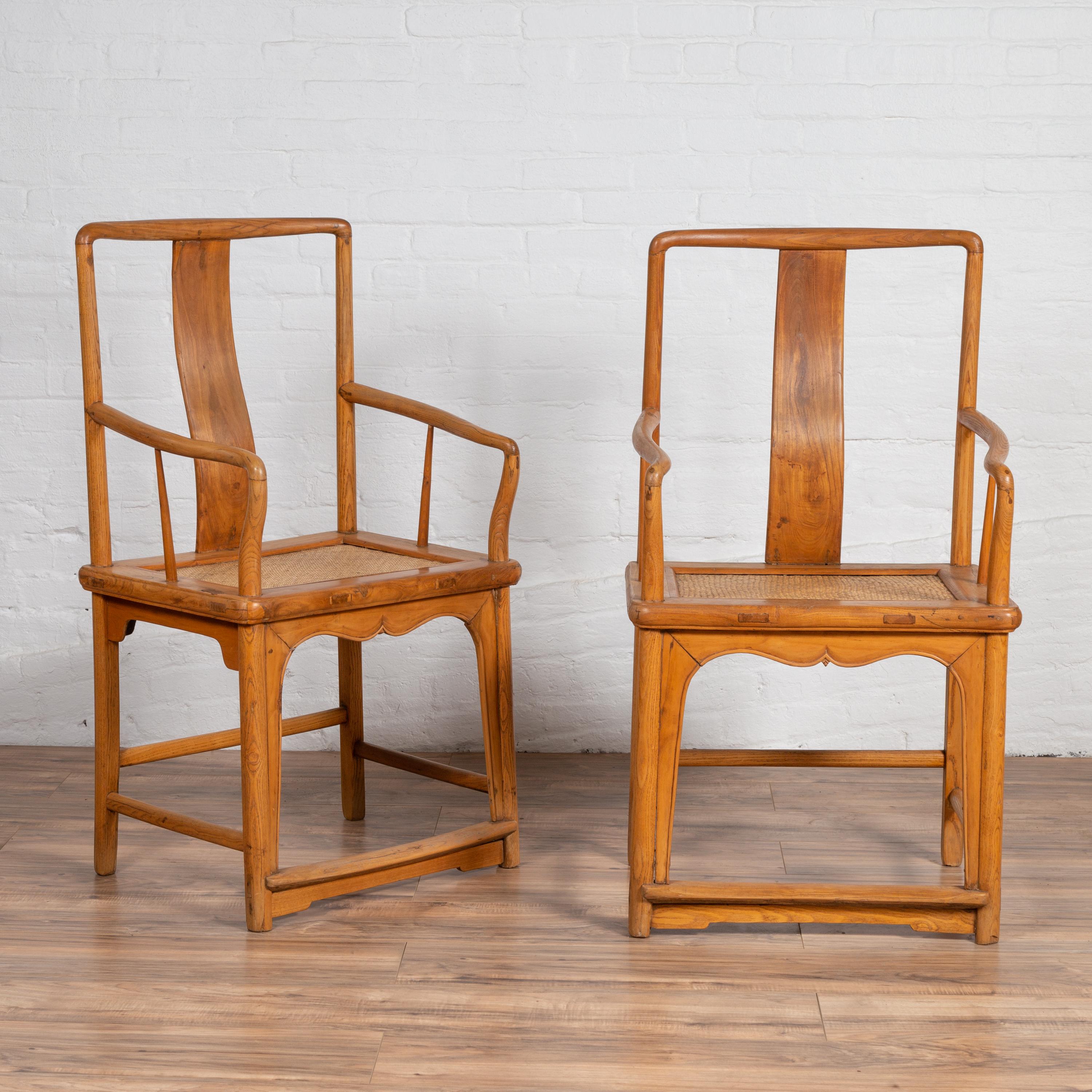 A near pair of Chinese Ming dynasty style vintage wedding armchairs from the mid-20th century, with woven rattan seats, curving armrests and natural wood patina. Born in China during the midcentury period, each of this near pair (they present slight