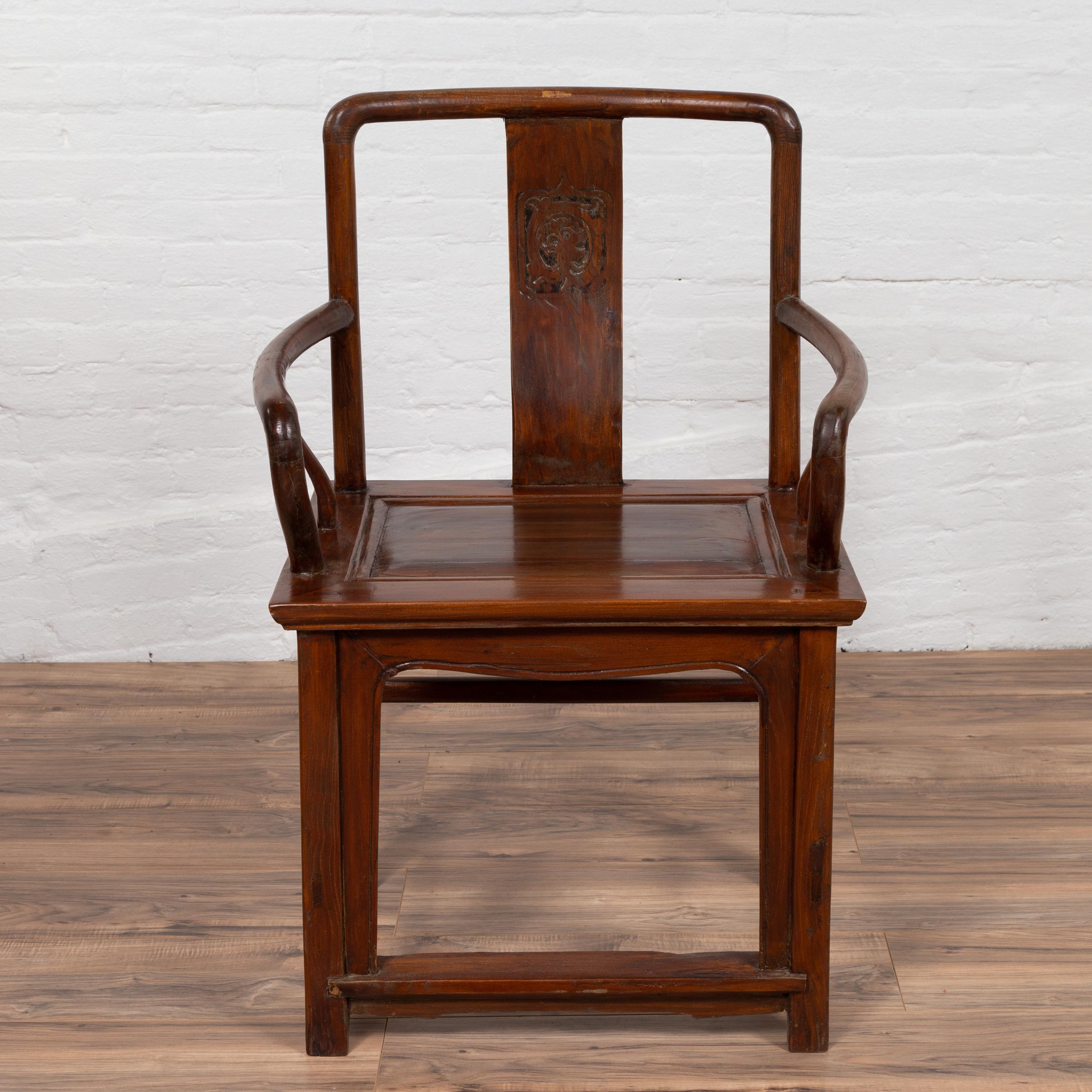 An antique Chinese Ming Dynasty style wooden wedding chair from the early 20th century, with carved medallion, curving armrests and natural wood patina. Born in China during the early years of the 20th century, this exquisite armchair features an