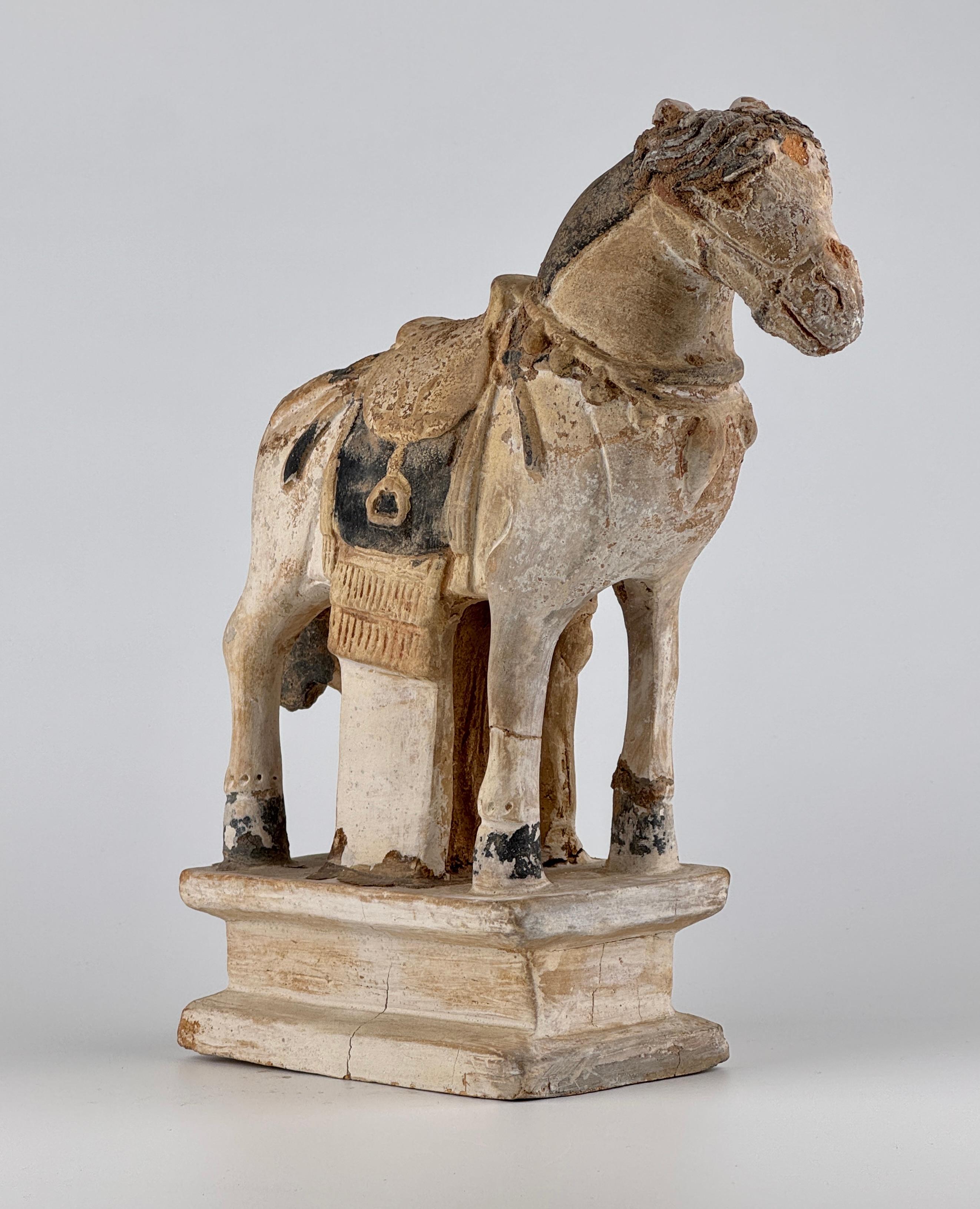 This Ming Dynasty painted pottery horse is depicted standing on a tiered rectangular pedestal. The horse has a well-proportioned body, with sturdy legs and a slightly arched neck. The eyes and muzzle are subtly outlined and incised.

The mane is