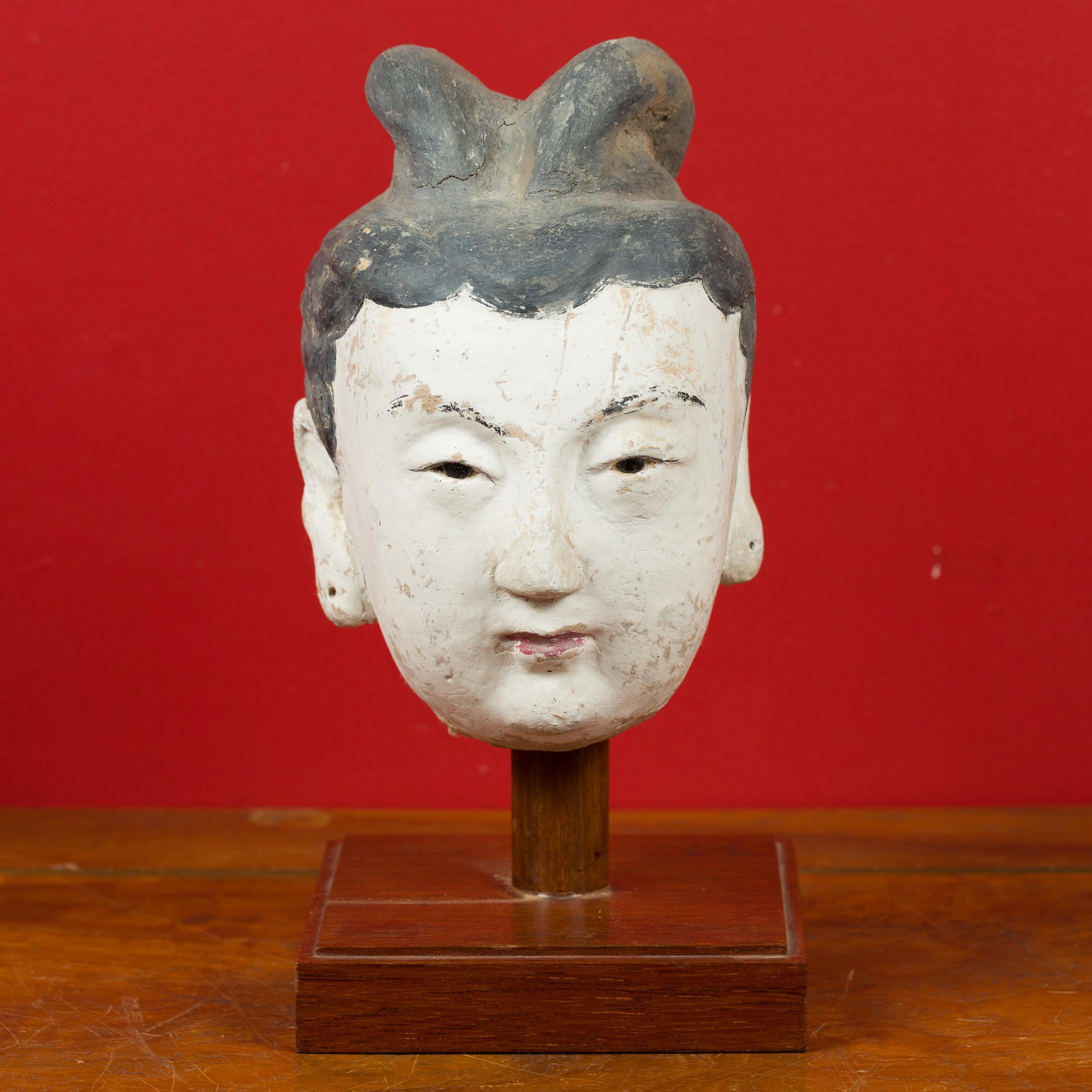 A Chinese Ming Dynasty period stucco head of a court lady from the 15th or 16th century, mounted on a wooden stand. Crafted in China during the Ming Dynasty, this stucco head is mounted on a custom made square wooden base, whose darker tones and