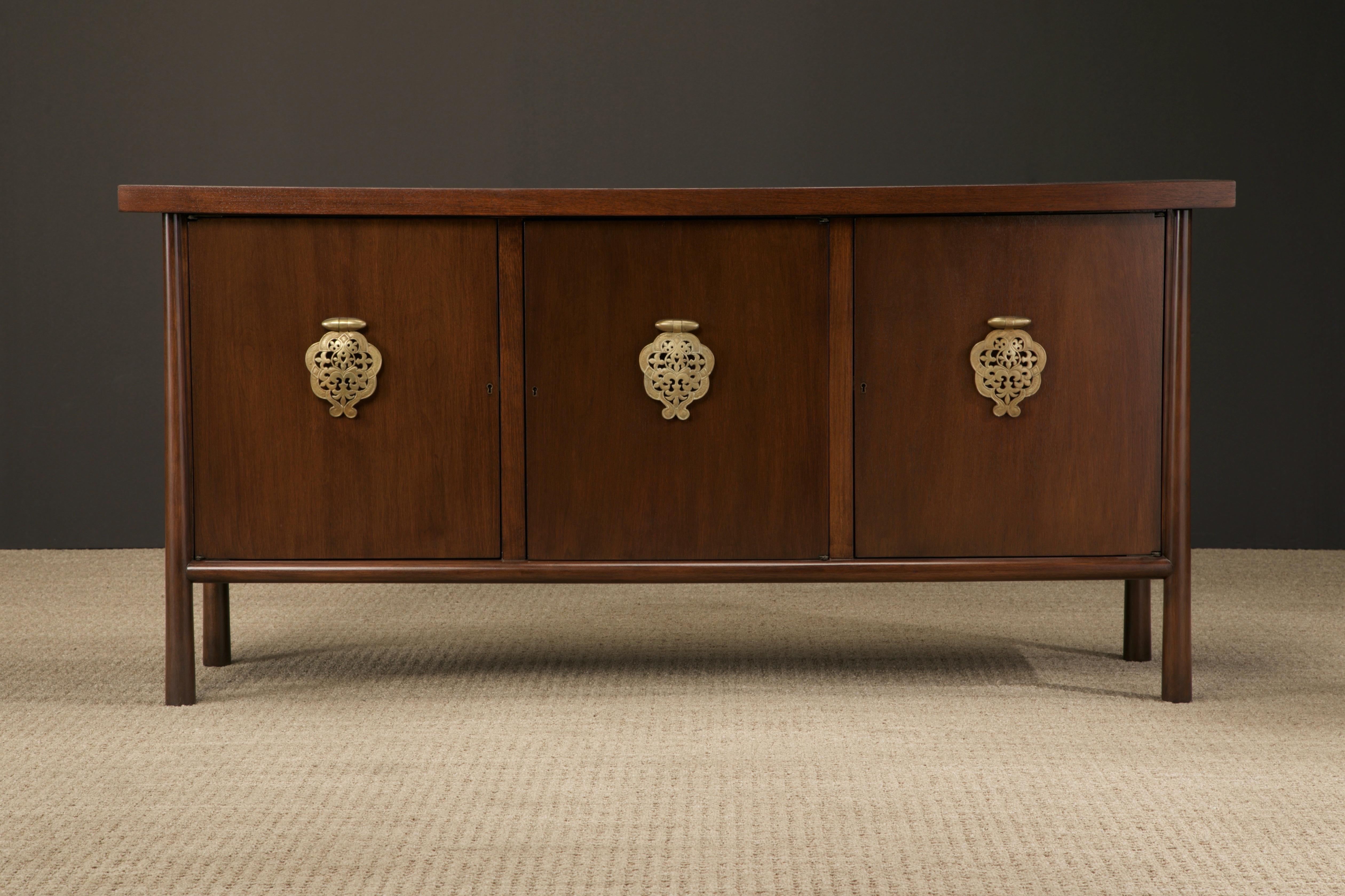 This elegant fully restored 'Ming' sideboard by T.H. Robsjohn-Gibbings for Widdicomb (USA) features gorgeous walnut grain with large brass handles. The center cabinet has four internal pull out drawers, the top two with fabric lined silverware