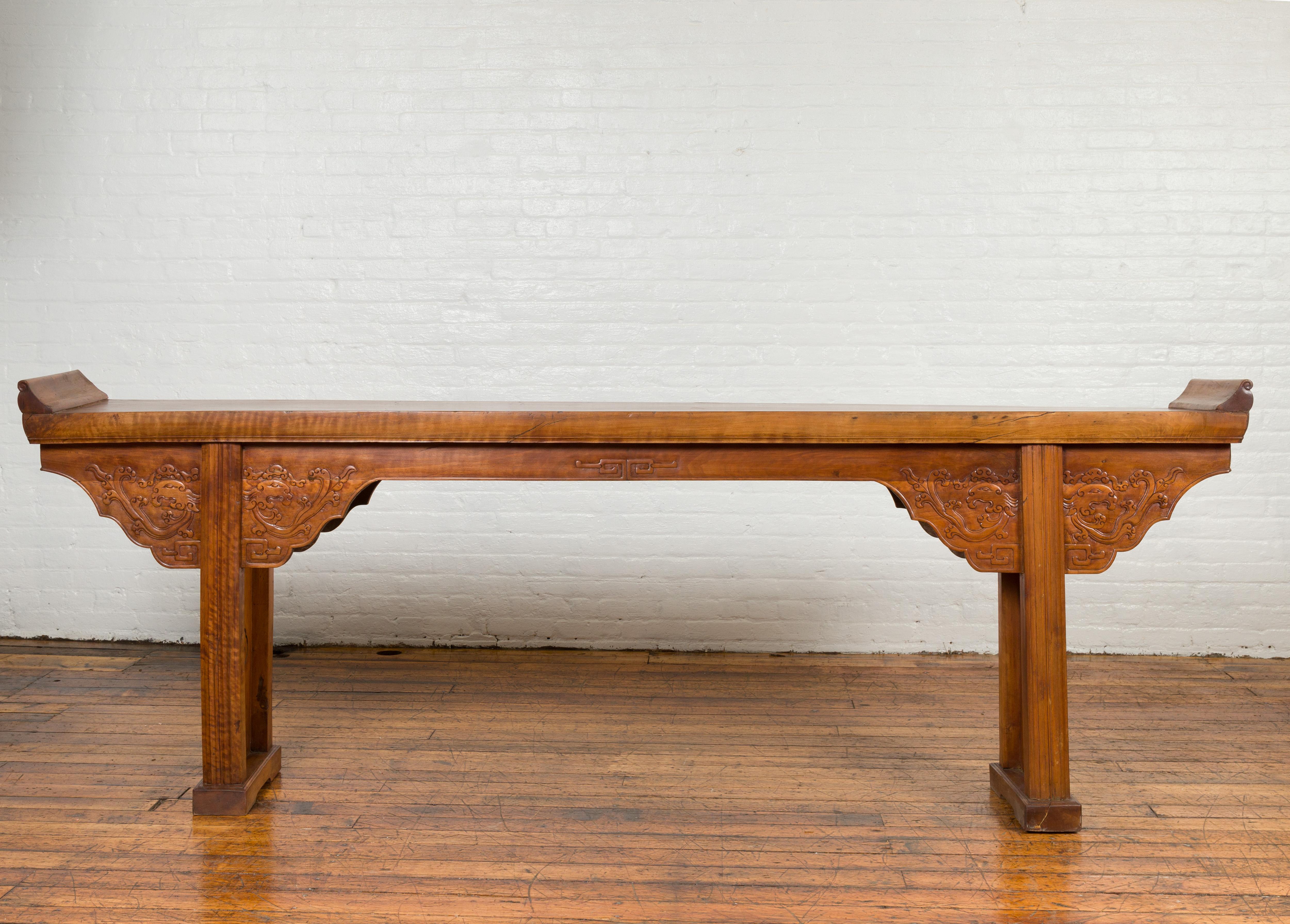 A Chinese Ming Dynasty style altar console table with carved apron, everted flanges, cloud motifs and mythical creatures. Attracting our attention with its elegant lines and skillfully carved décor, this Chinese Ming Dynasty style console altar