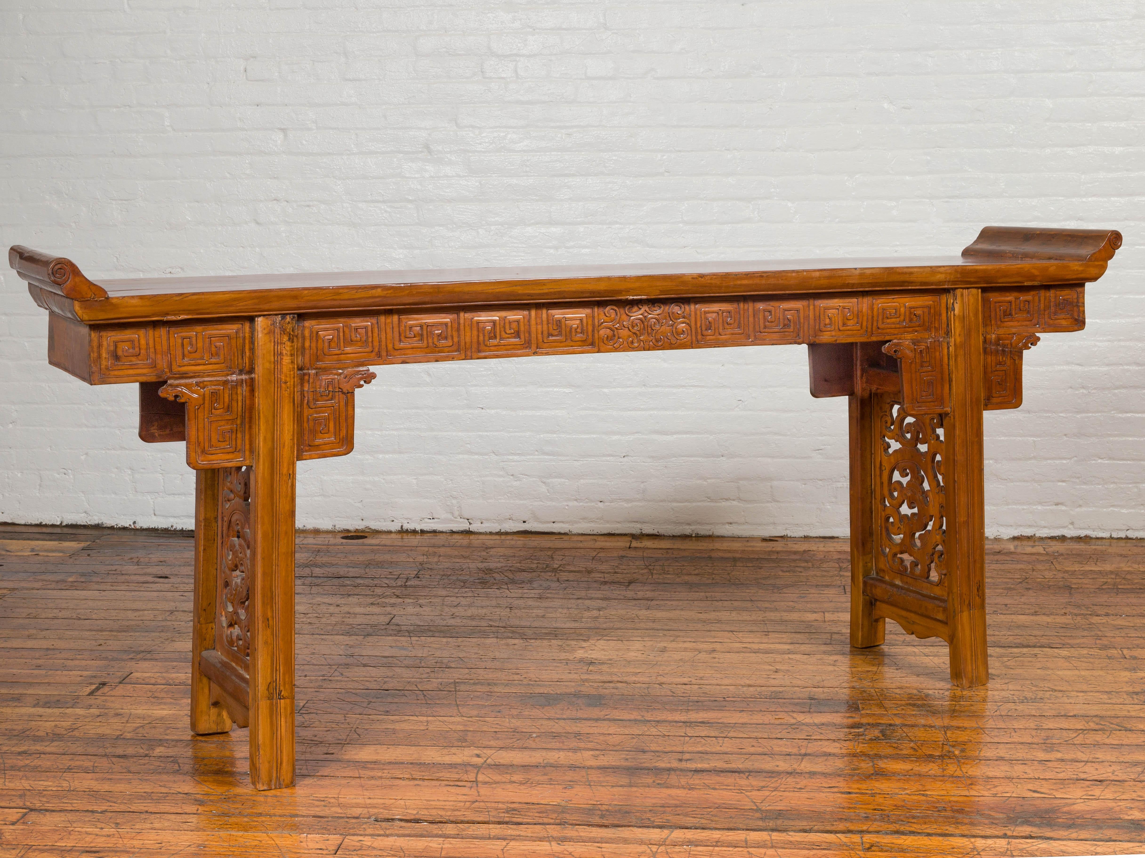 A Chinese Ming Dynasty style altar console table with meander-carved apron, everted flanges and cloud motifs. Attracting our attention with its elegant lines and skilfully carved décor, this Chinese Ming Dynasty style console altar table features a
