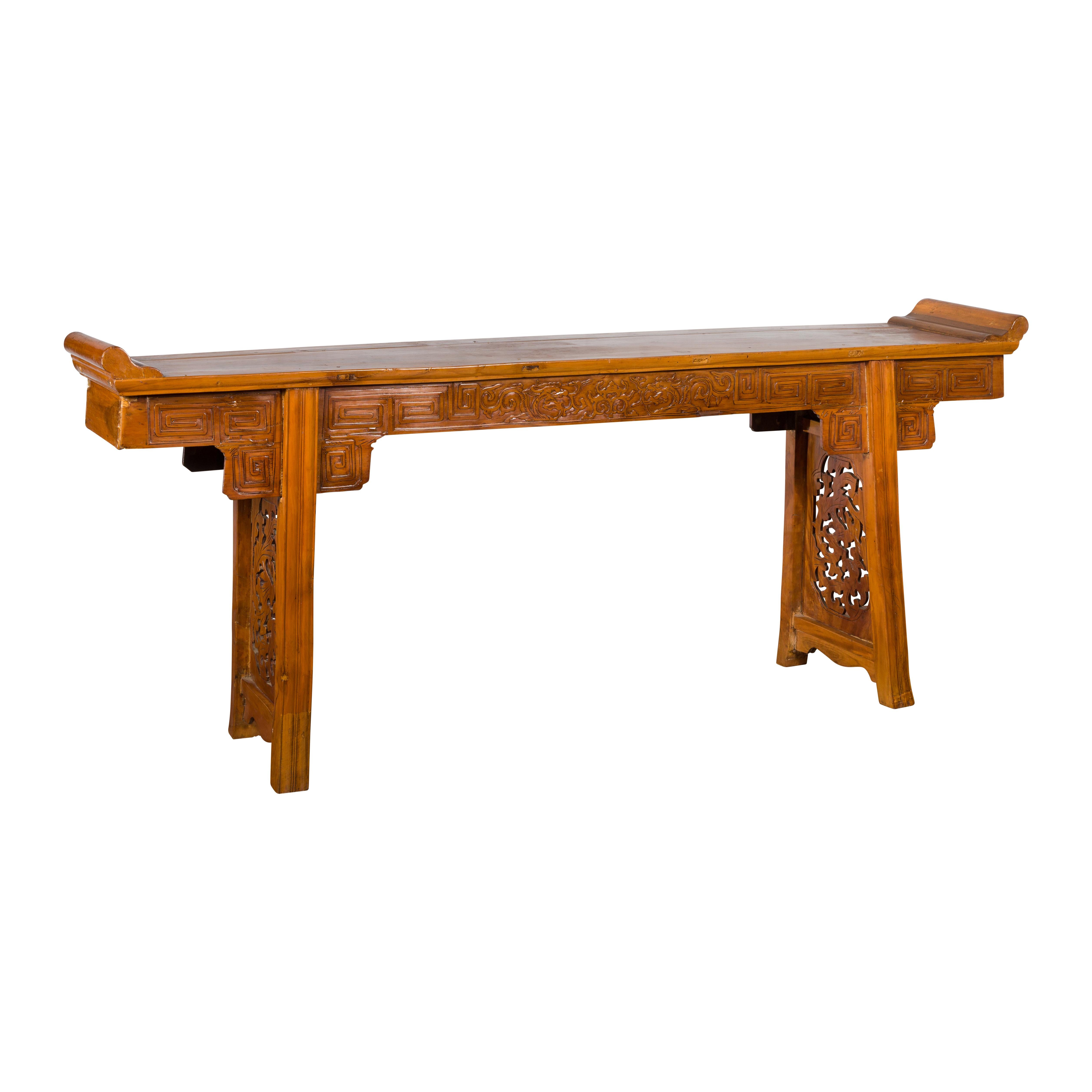 A Chinese Ming Dynasty style altar console table from the early 20th century, with meander-carved apron, everted flanges and dragon motifs. Created in China during the second quarter of the 20th century this Ming style console altar table features a