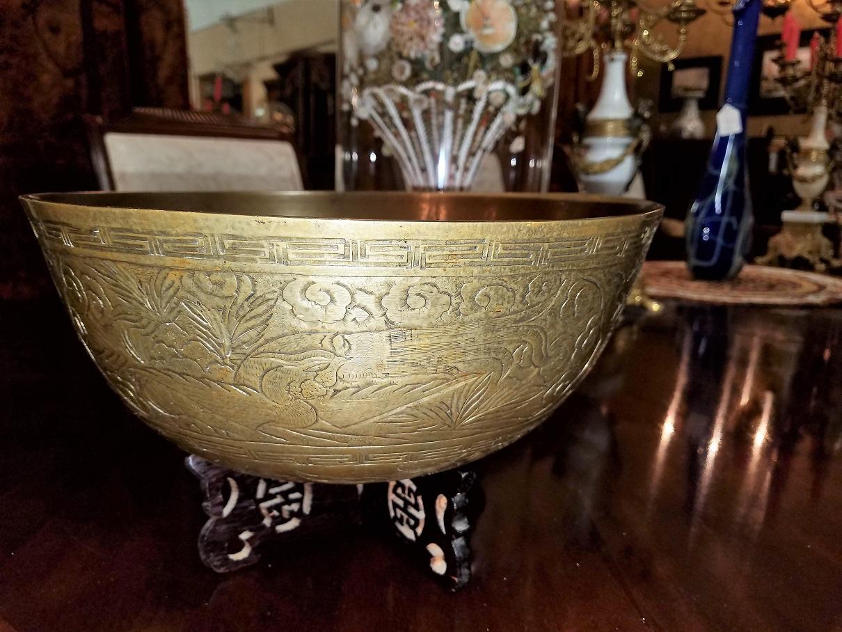 Presenting an early 20th century reproduction of a Ming dynasty bronze centre bowl.

The bowl is solid bronze/brass. It sits on its original interlocking rosewood stand with Chinese symbols.

The exterior of the bowl is profusely engraved with a