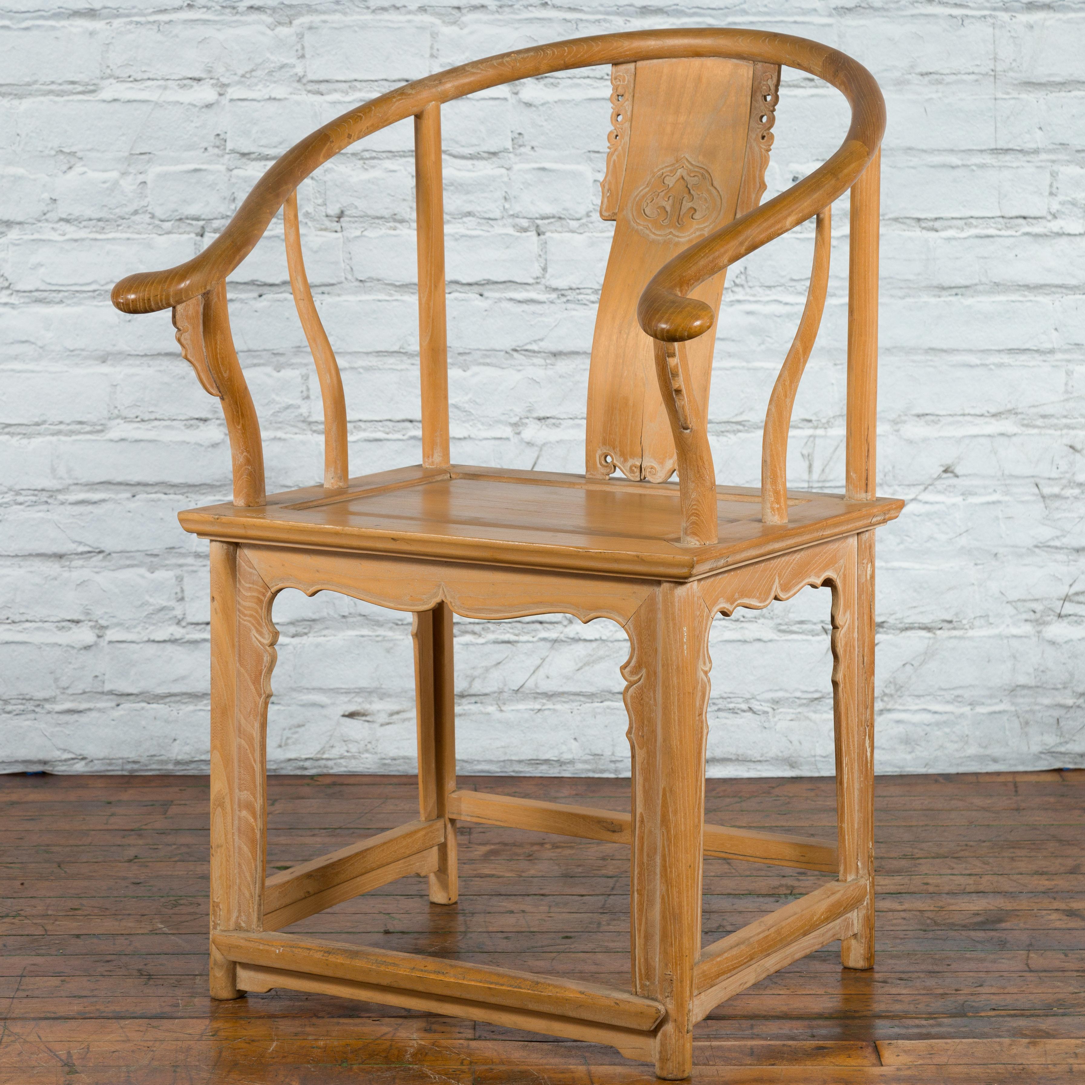 A Chinese Ming dynasty style natural wood horseshoe back armchair from the mid 20th century, with carved splat and apron. Born in China during the mid-century period, this armchair charms our eyes with its natural wooden finish and graceful lines.