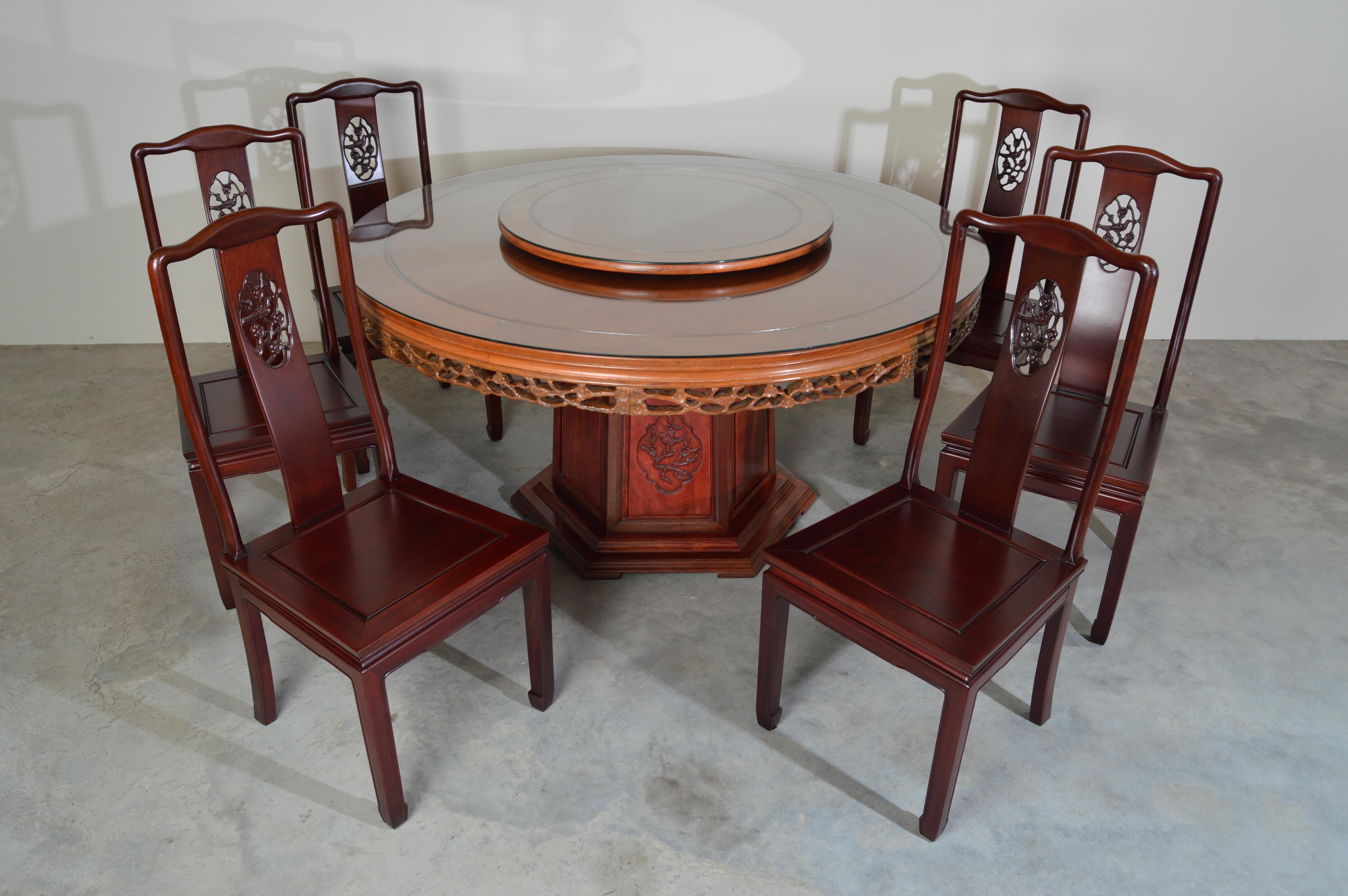 Solid Honey rosewood, 60 inch round bird & flower carved 7 piece dining set and lazy Susan.

Handsome solid rosewood Oriental dining room table with lazy Susan and 6 chairs having silk seat cushions. Crafted completely by hand with durable tongue