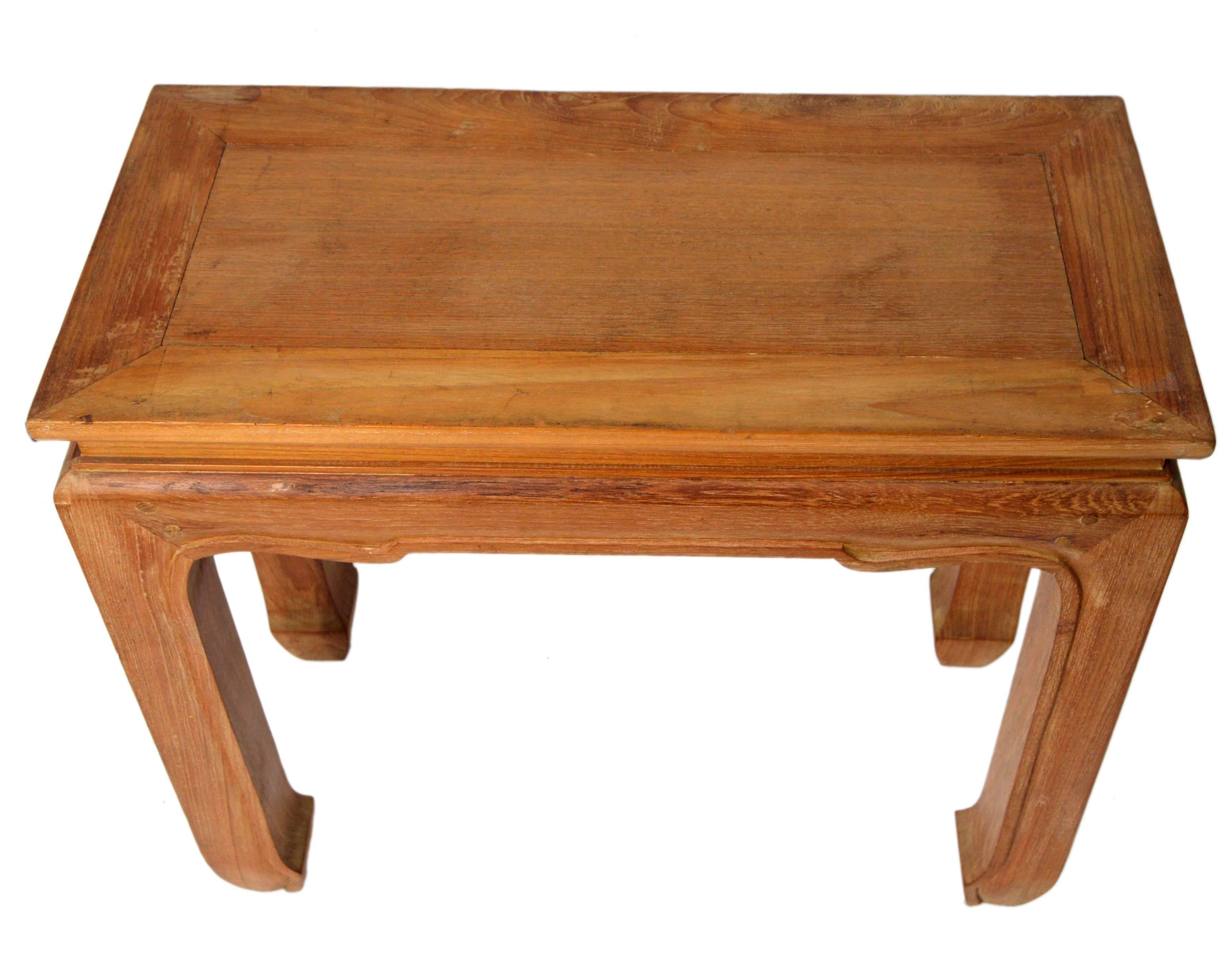 A vintage 1960s Ming style Chinese side table handmade from lacquered natural wood. This small rectangular side table features a rectangular top sitting above a recessed molding, over a delicately carved apron. The table is raised on four